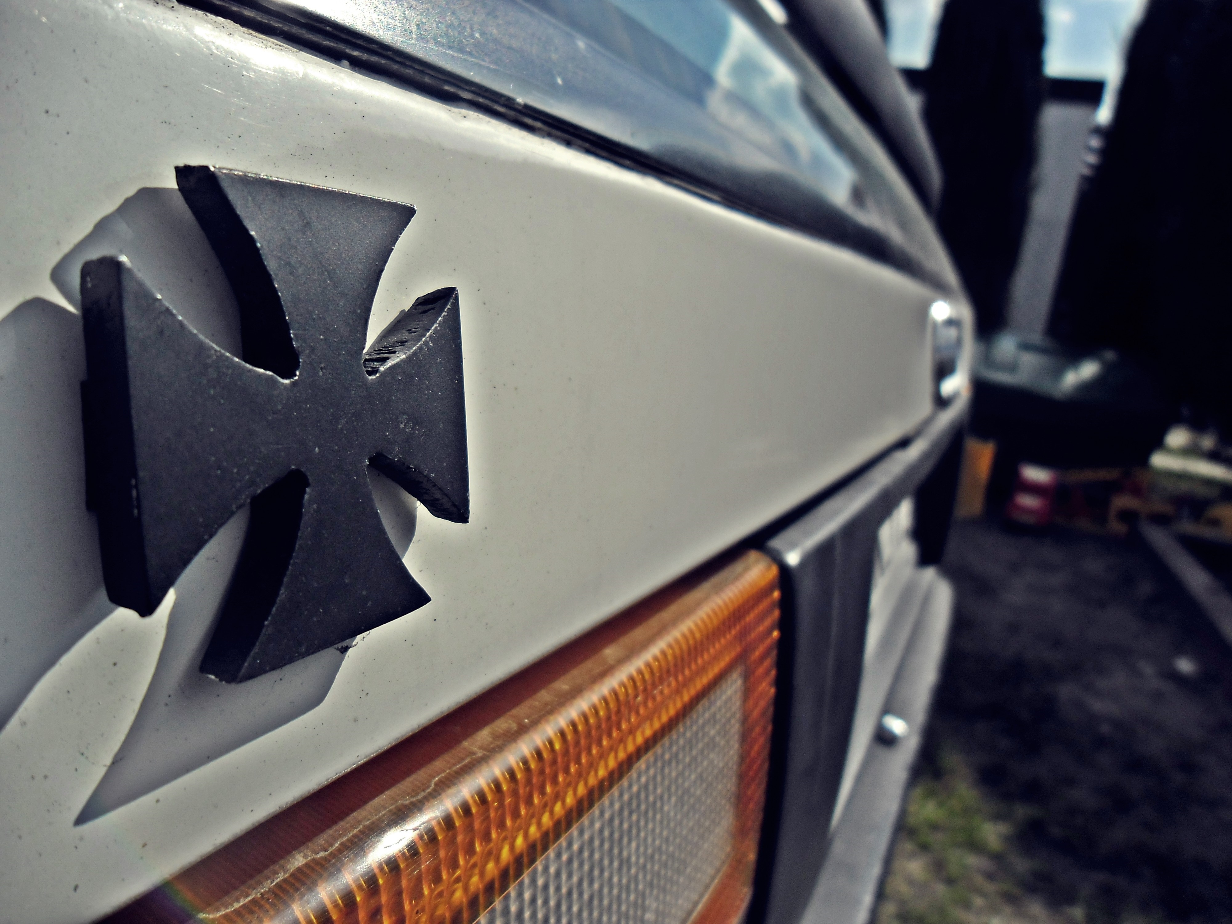 Close-up of a black Iron Cross emblem on a white car HD Wallpaper