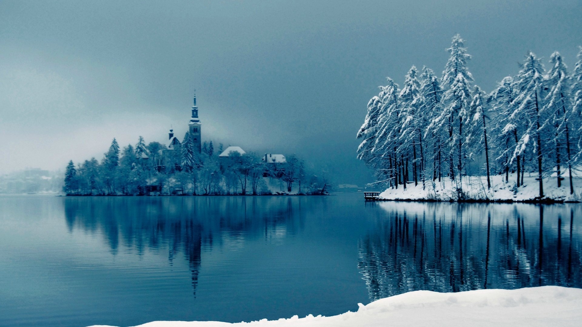 Winter island with church reflected in a lake HD Wallpaper