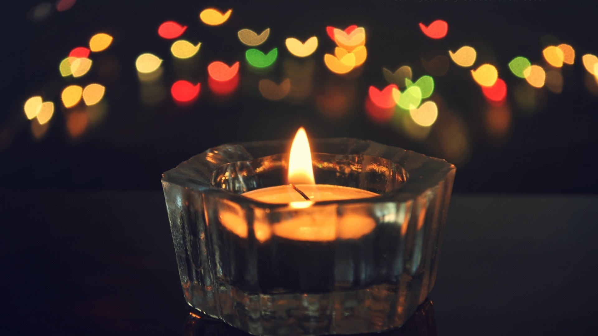 Candle flame in a glass holder with bokeh lights HD Wallpaper