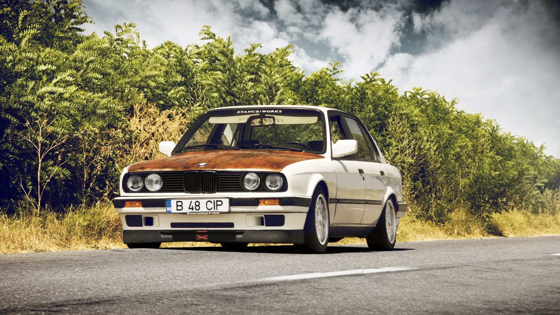 White BMW E30 sedan with rusty hood on a road HD Wallpaper