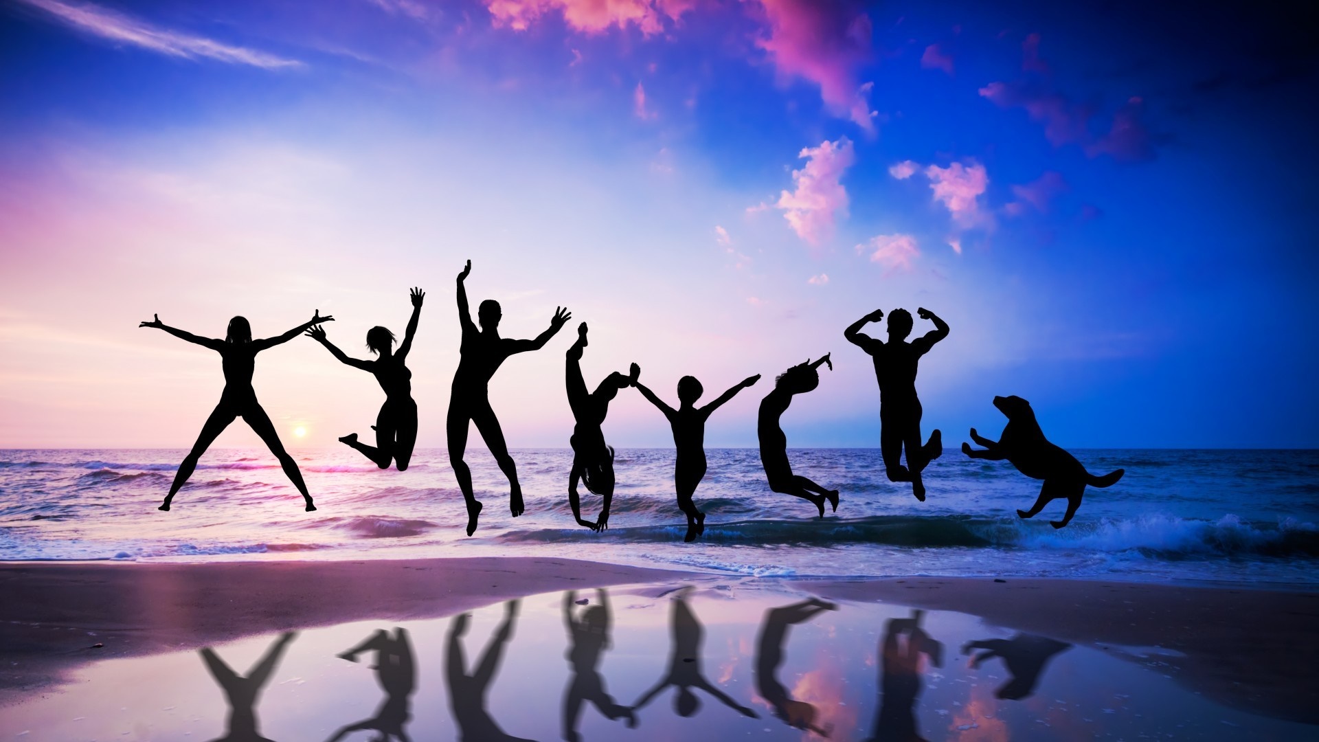 Silhouettes of people and a dog jumping on a beach at sunset HD Wallpaper