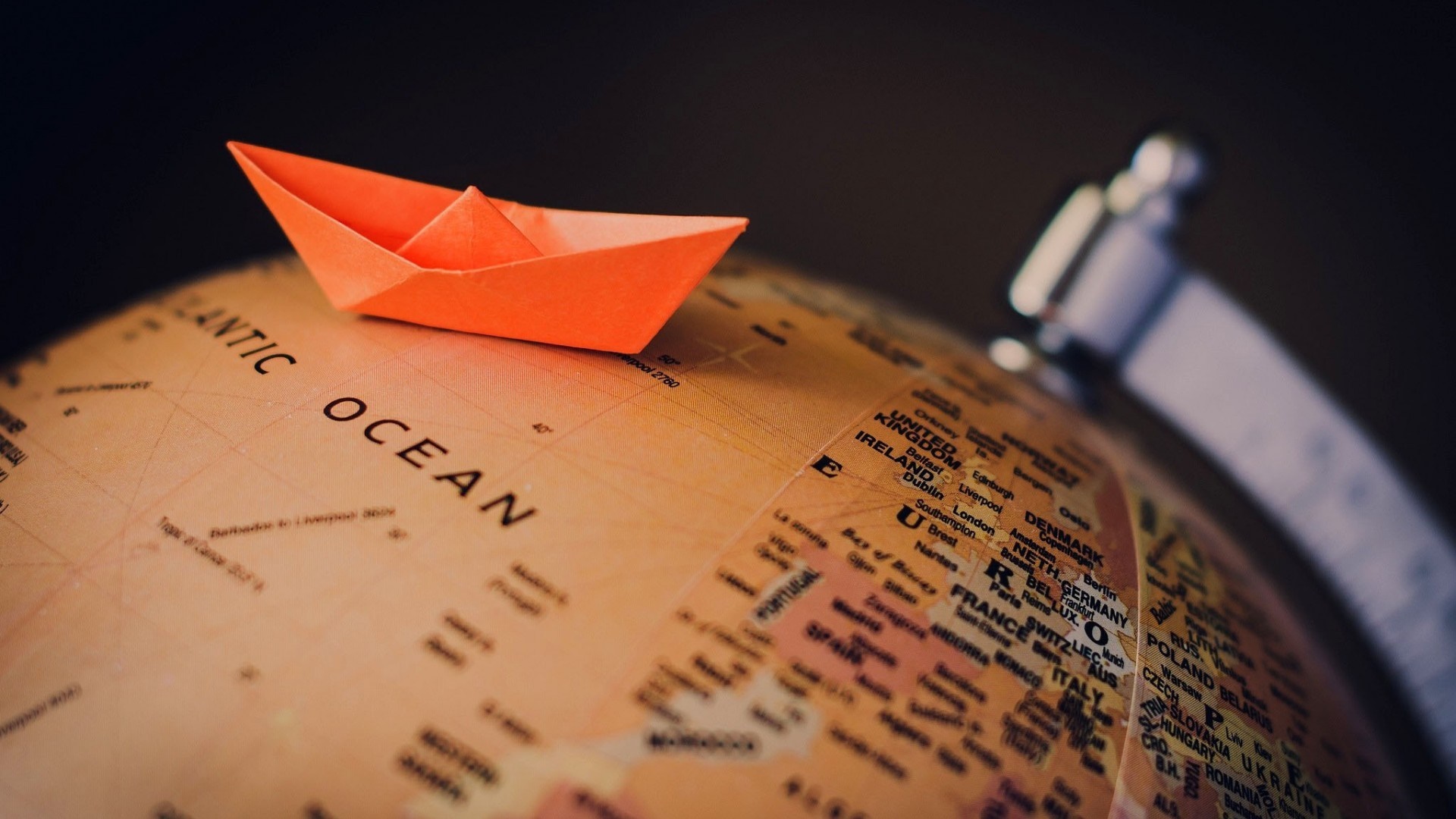 Orange paper boat on a globe HD Wallpaper