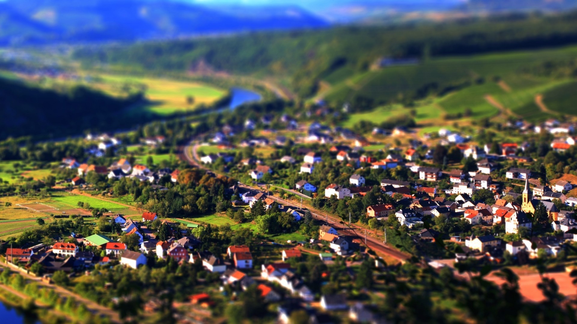 Aerial view of a village nestled in a valley with rolling hills HD Wallpaper