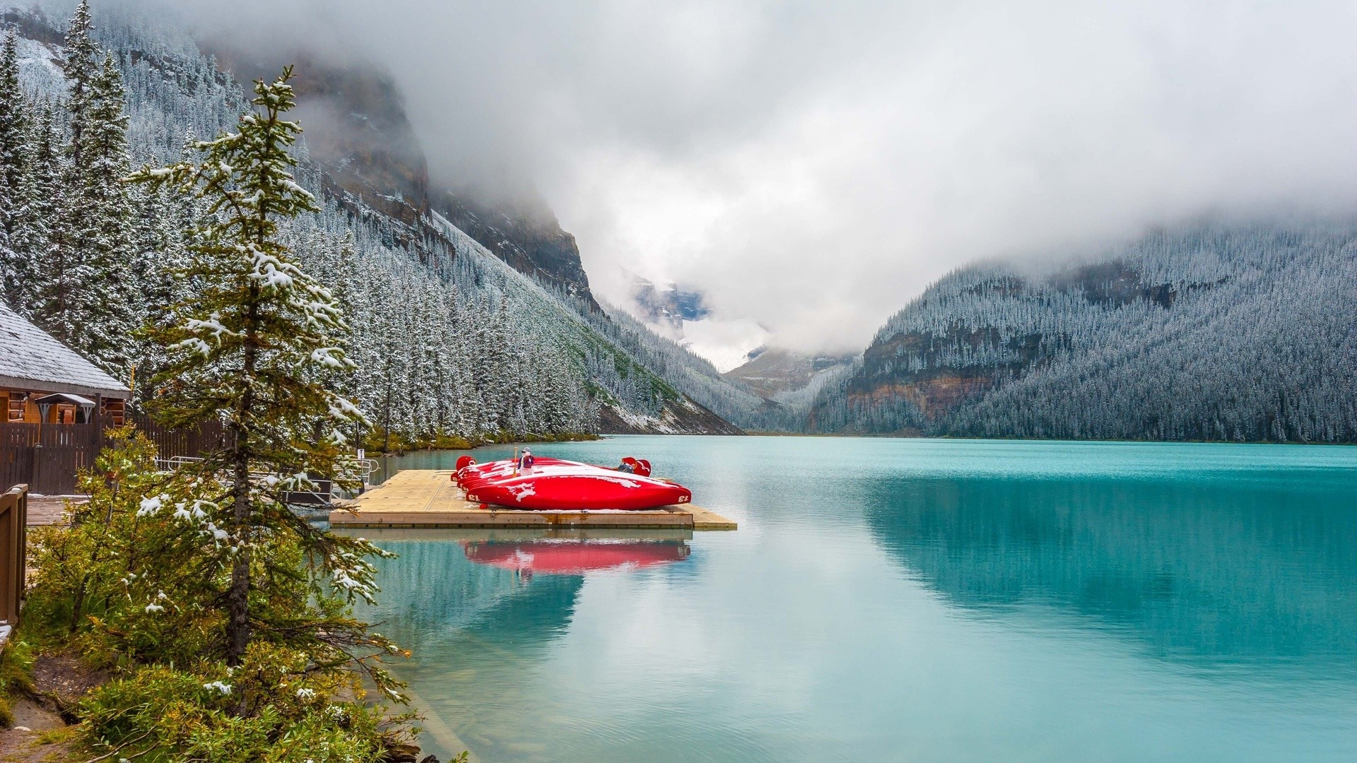 Red canoes on a dock in a snowy mountain lake HD Wallpaper