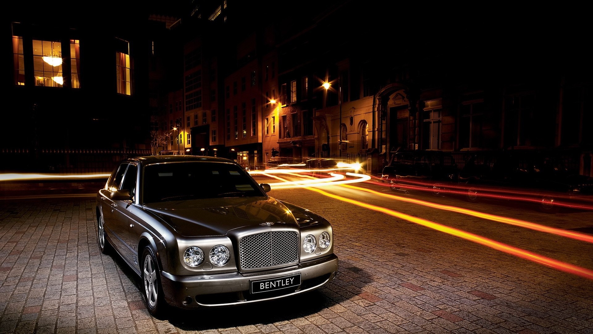 Bentley sedan parked on a cobblestone street at night HD Wallpaper