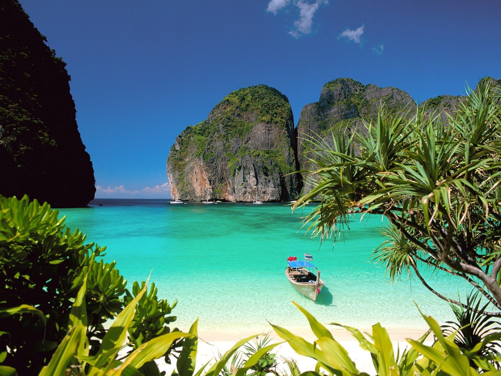 Tropical island bay with limestone cliffs and a longtail boat HD Wallpaper