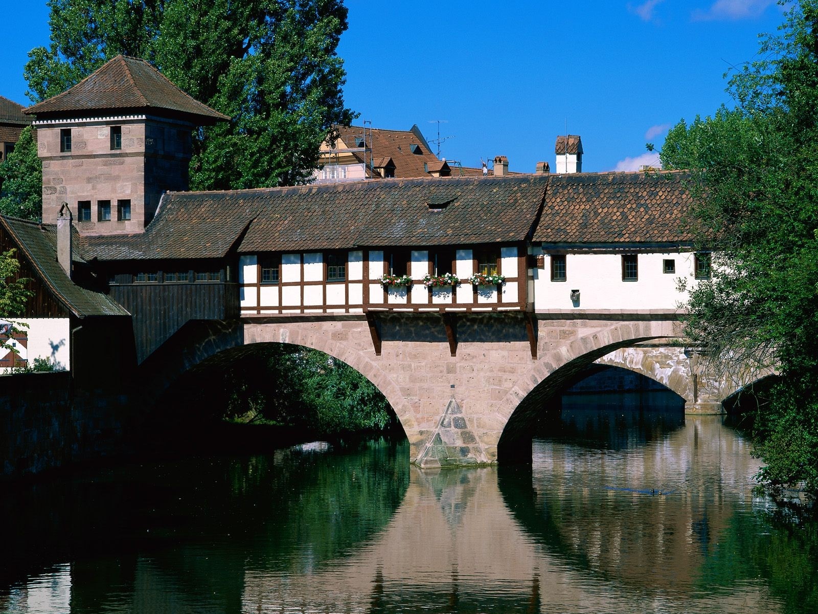 Covered bridge over a river with stone arches HD Wallpaper