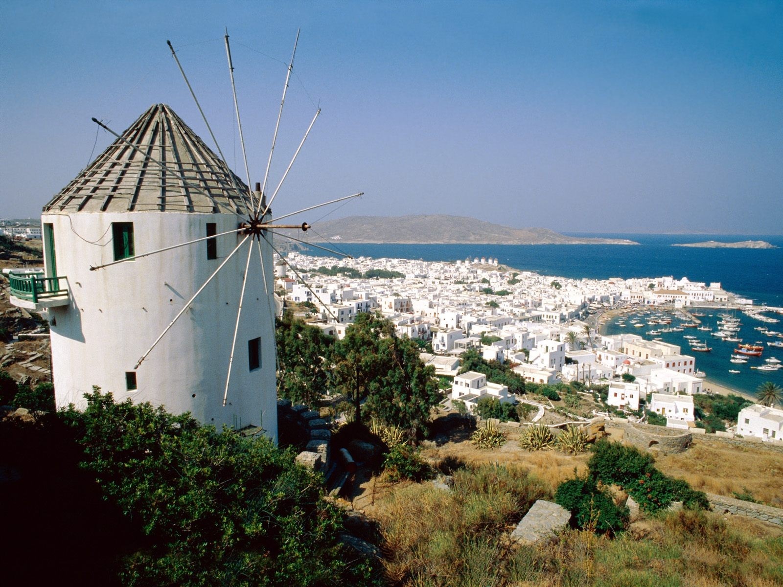 White windmill overlooking a coastal town and the sea HD Wallpaper
