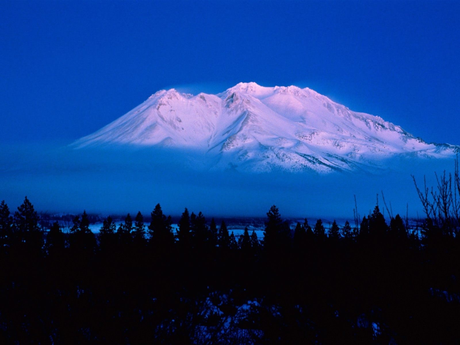 Snow-covered mountain peak at dusk with clouds and trees HD Wallpaper