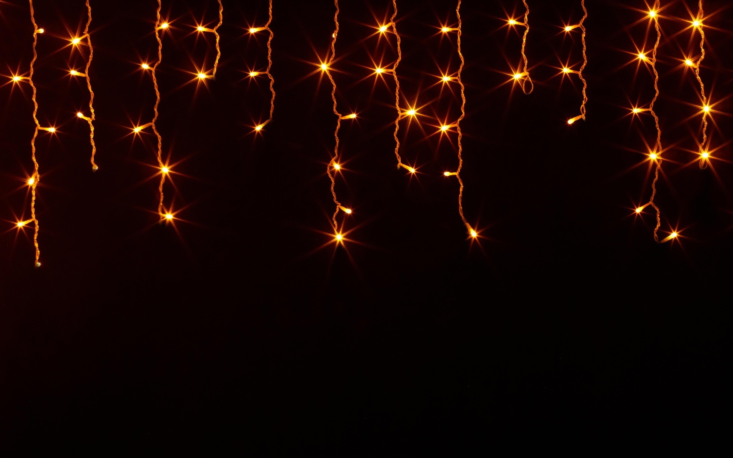 String of orange lights on black background HD Wallpaper