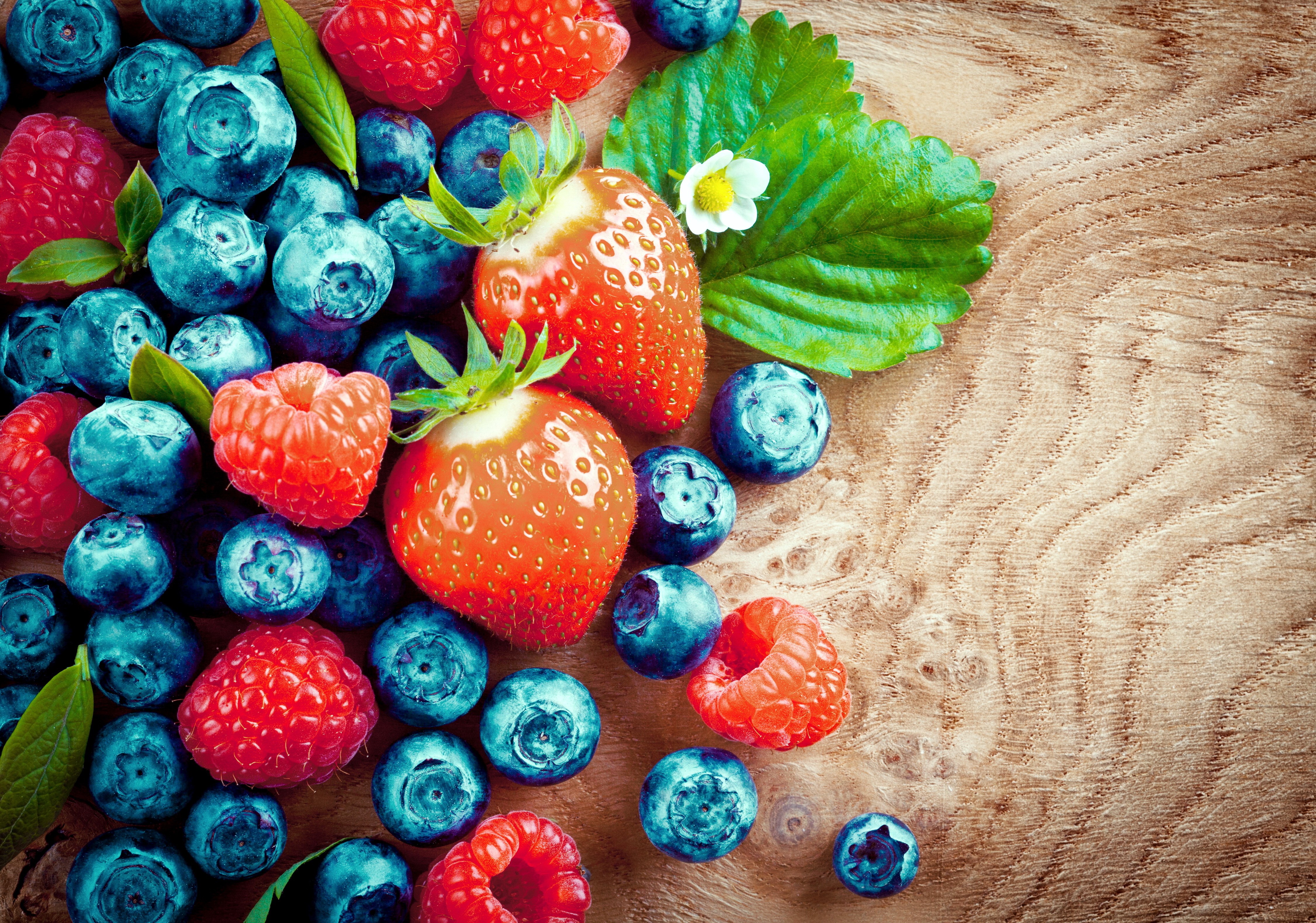 Berries and strawberries on a wooden surface HD Wallpaper