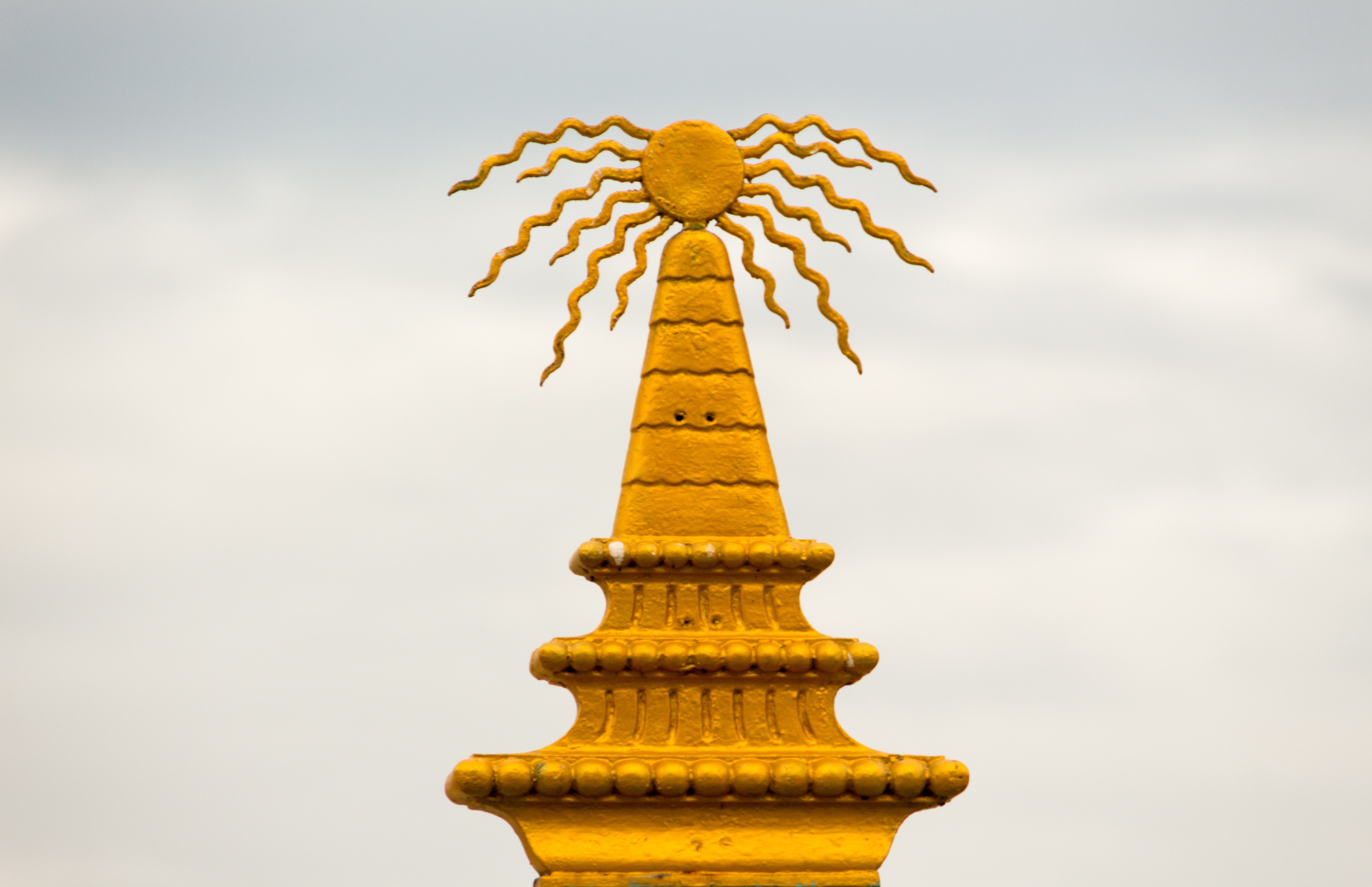 Golden sun symbol atop a tiered structure HD Wallpaper