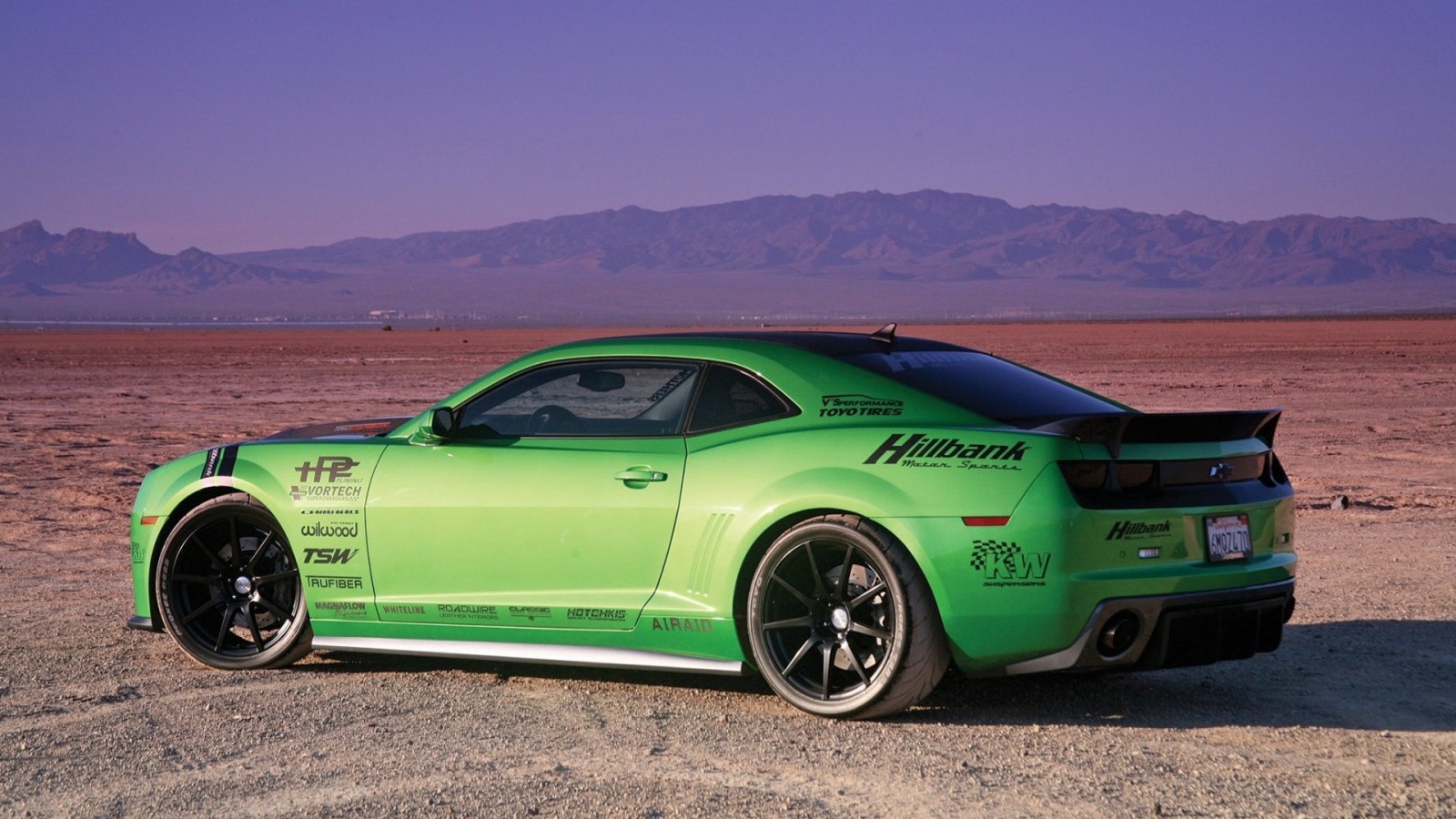 Green Chevrolet Camaro with racing decals in desert landscape HD Wallpaper