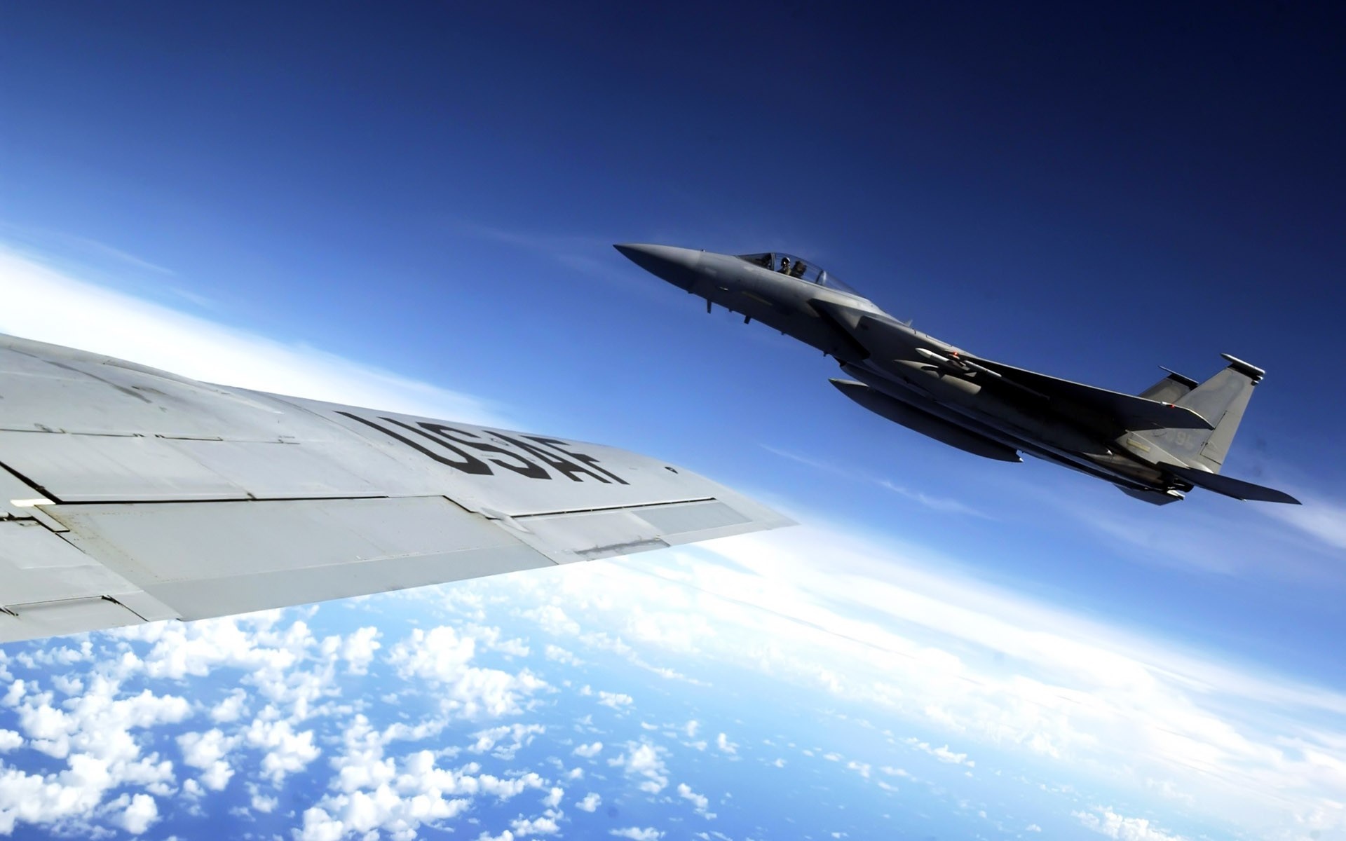 F-15 Eagle fighter jet flies near a USAF aircraft wing HD Wallpaper