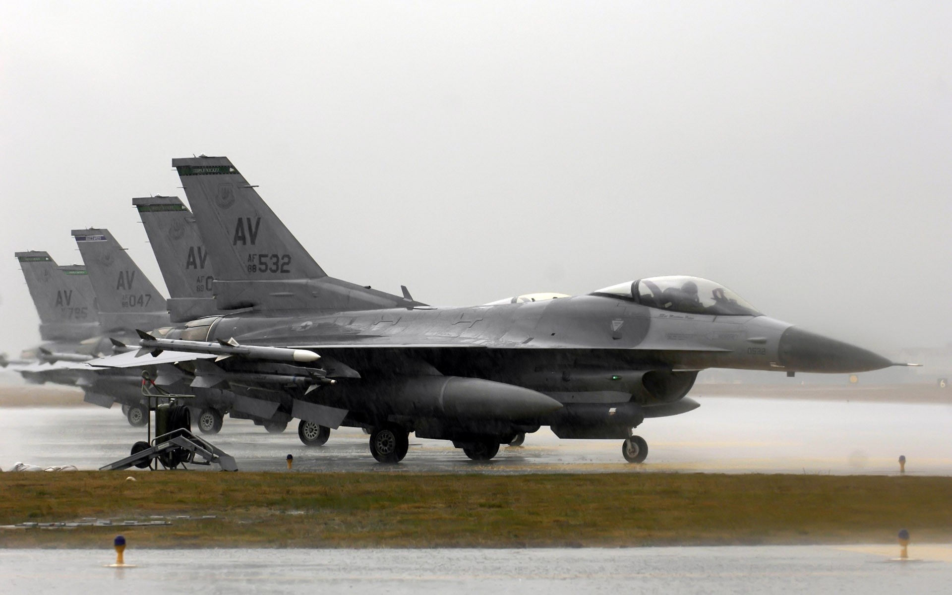 F-16 Fighting Falcon fighter jets on a wet tarmac HD Wallpaper