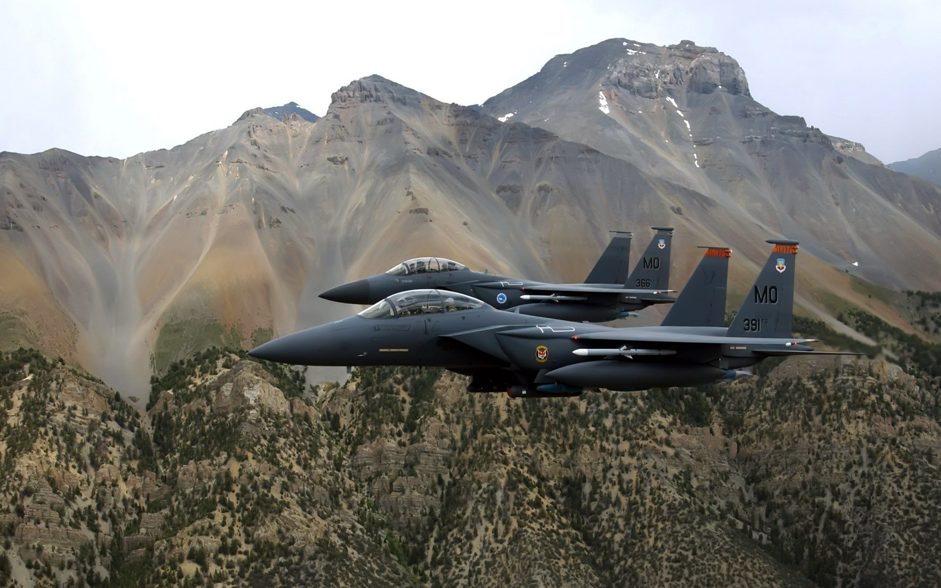 Two McDonnell Douglas F-15 Eagle fighter jets flying over mountains HD Wallpaper