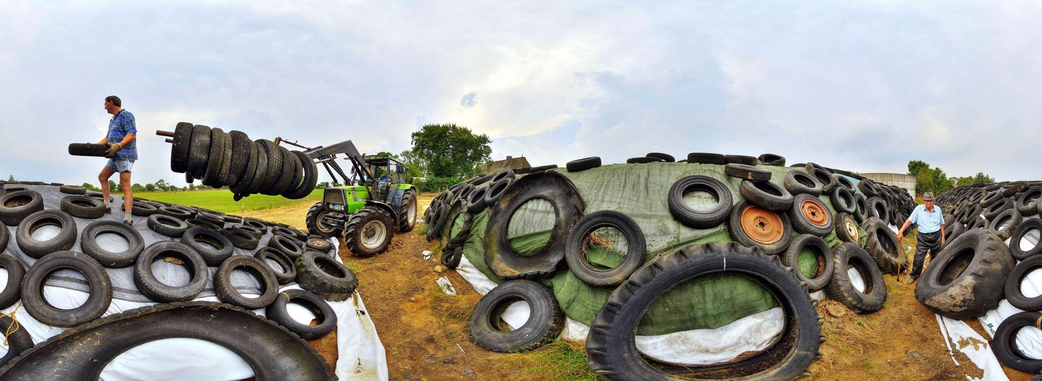 Tractor and men covering silage with tires HD Wallpaper