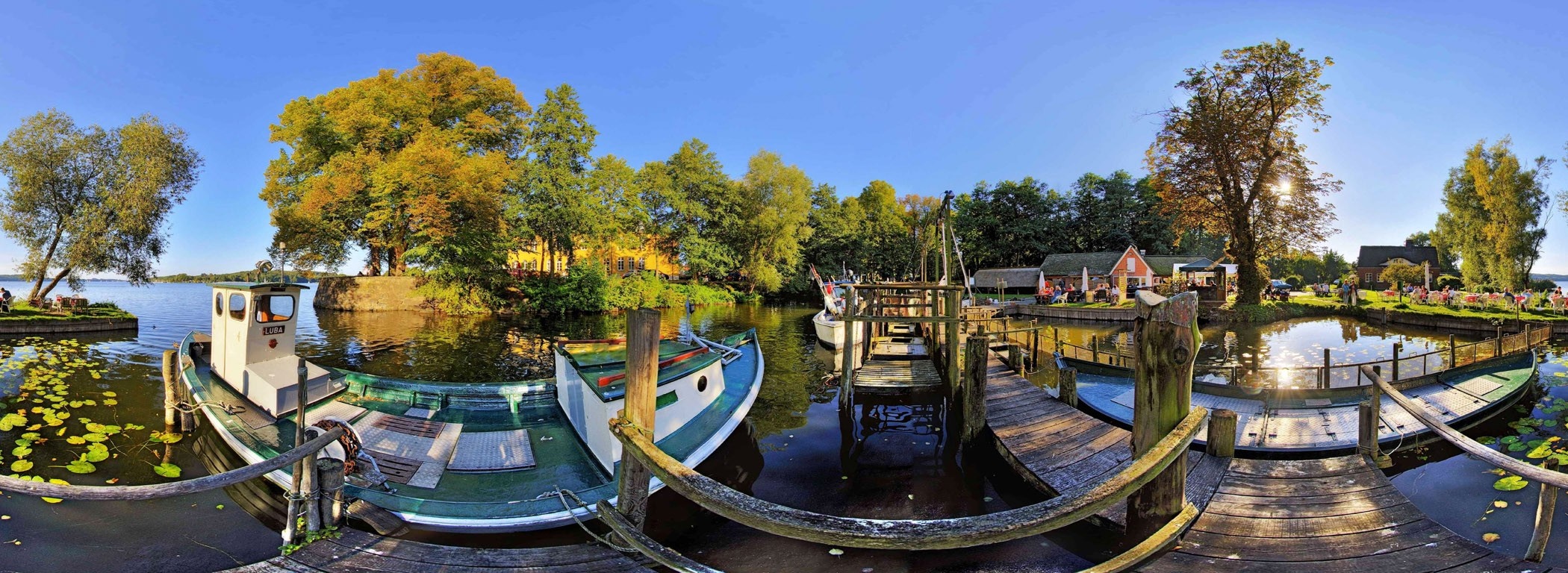 Boats docked at a scenic waterfront with trees and buildings HD Wallpaper
