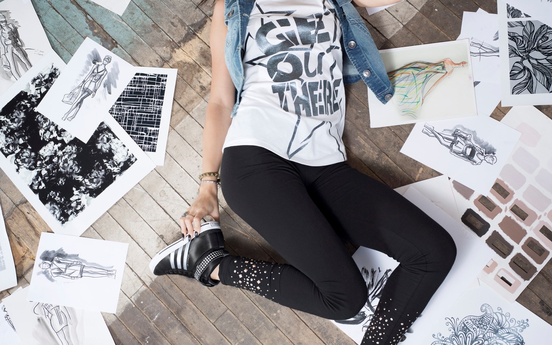 Woman in denim vest and leggings surrounded by fashion sketches HD Wallpaper