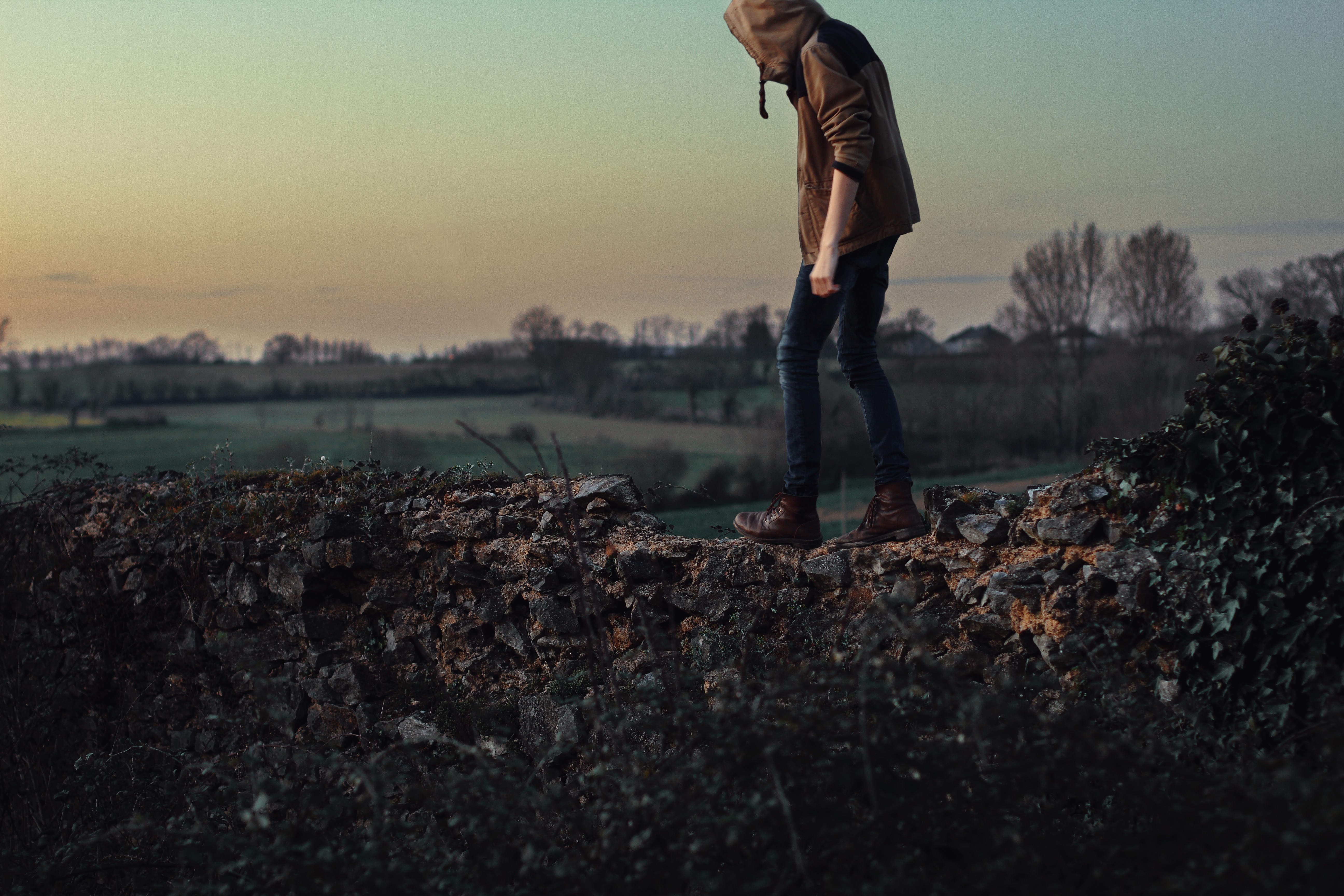 Person walking on a stone wall at sunset HD Wallpaper