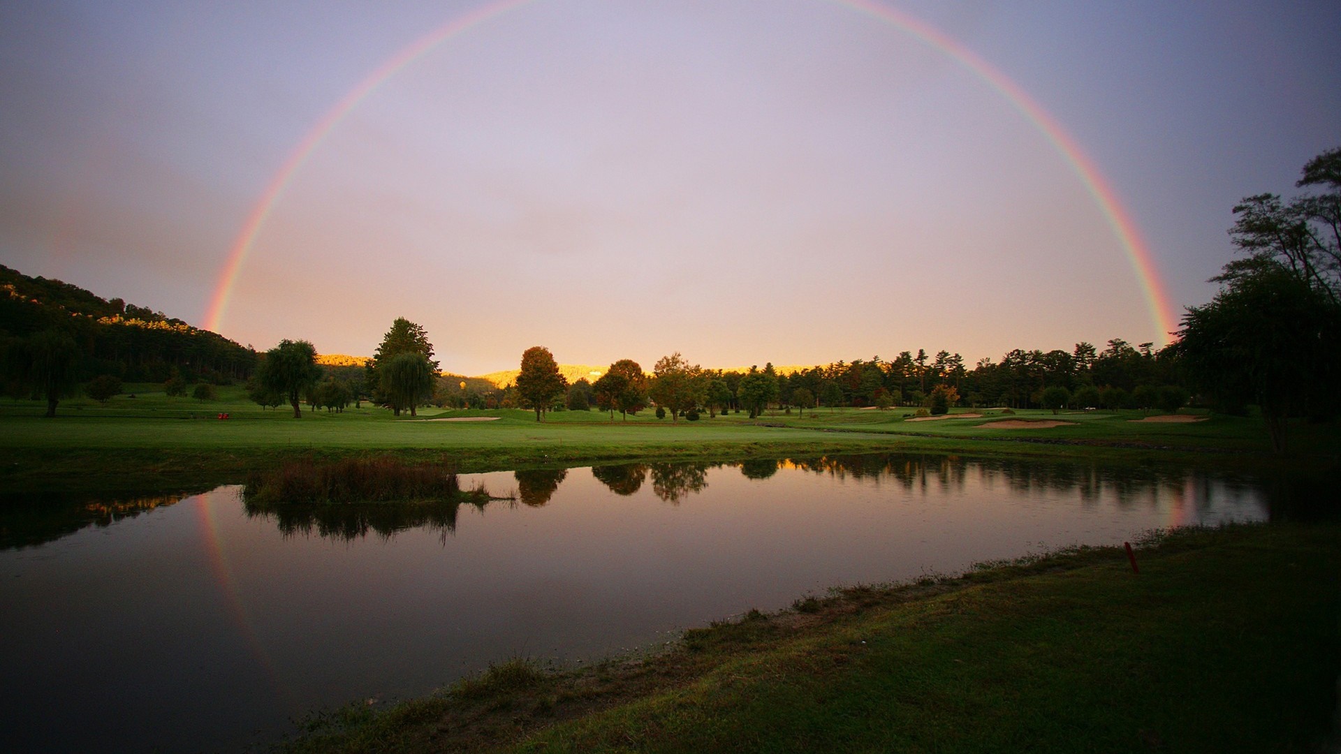Rainbow over a golf course with a pond at sunset HD Wallpaper