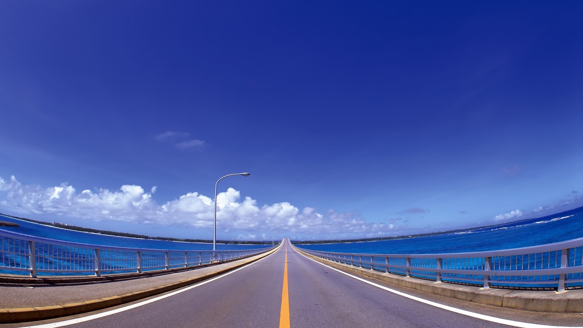 A long bridge over the ocean under a blue sky HD Wallpaper