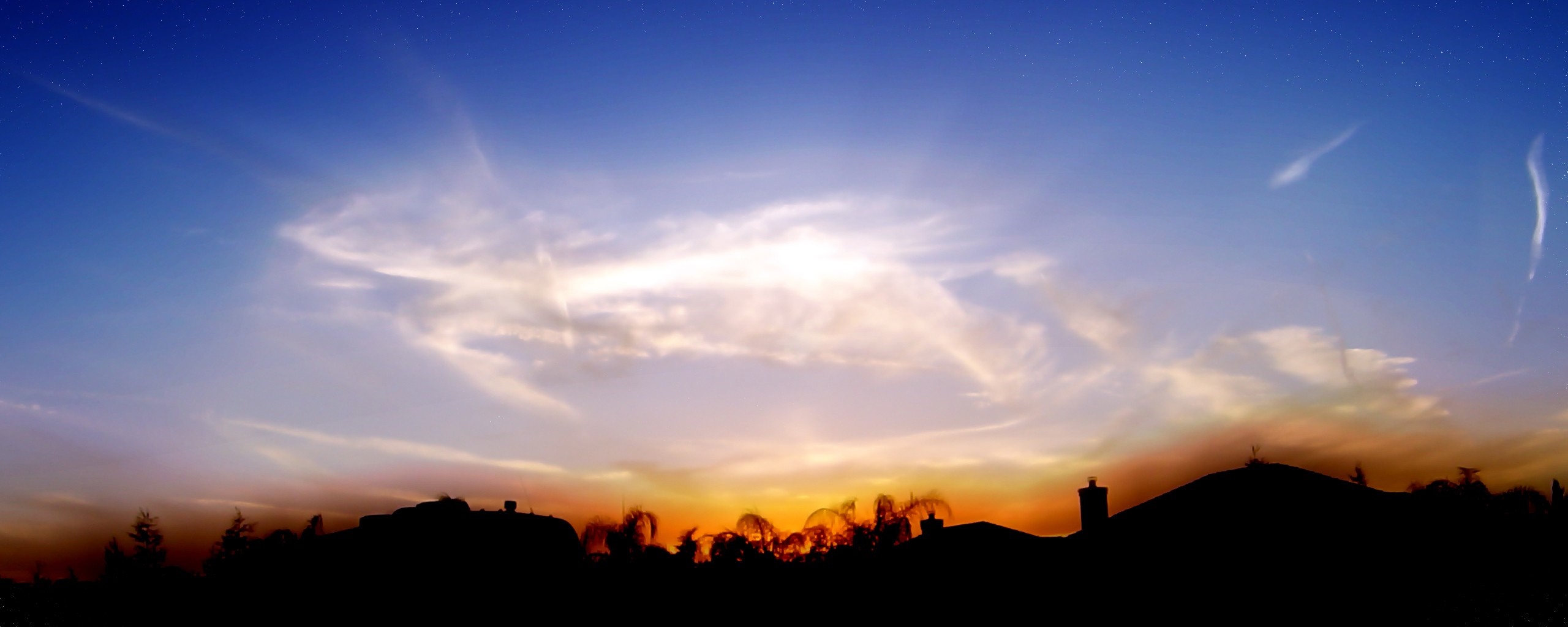 Sunset sky with clouds and contrail over silhouetted landscape HD Wallpaper