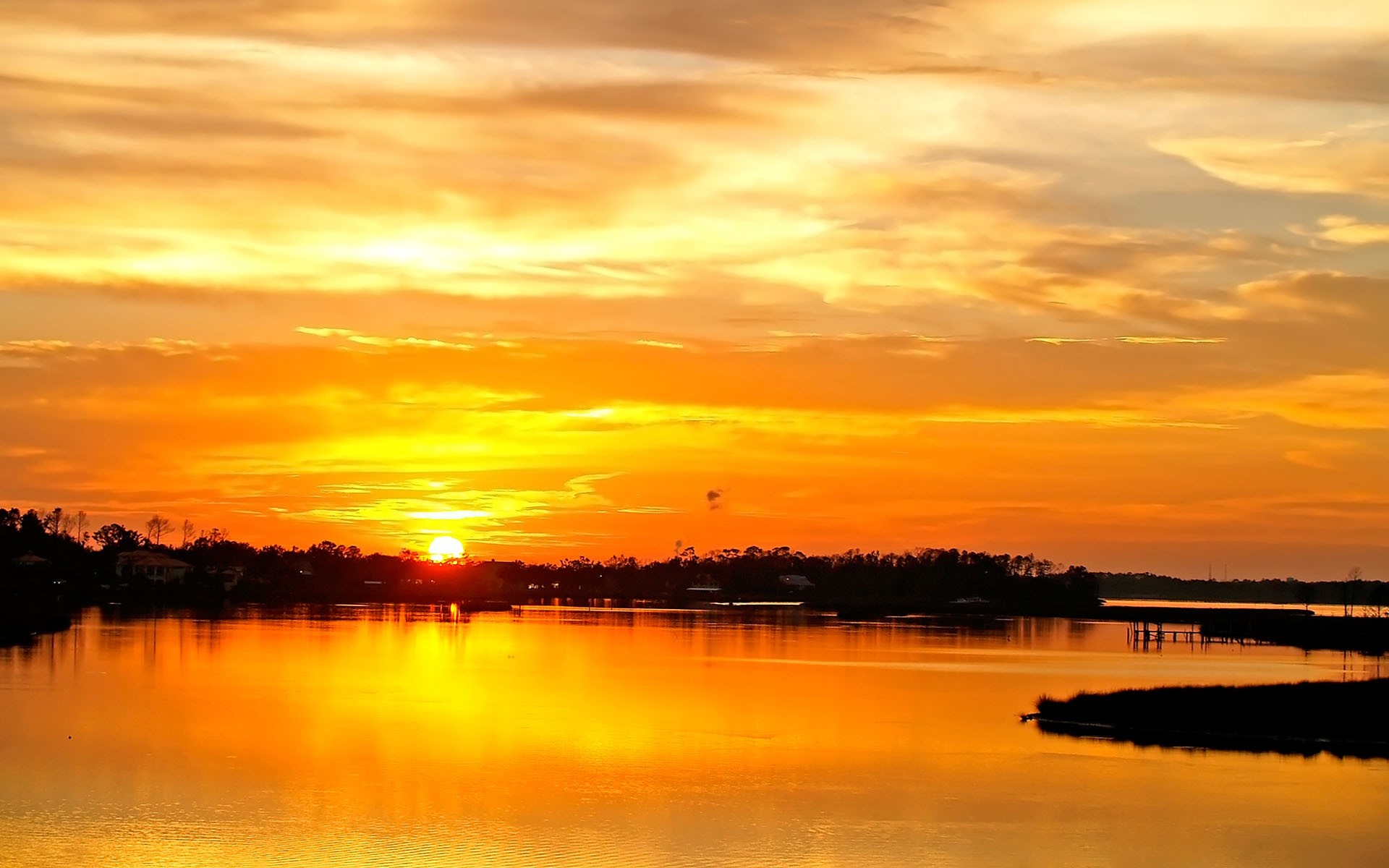 Sunset over a calm body of water with silhouetted trees HD Wallpaper