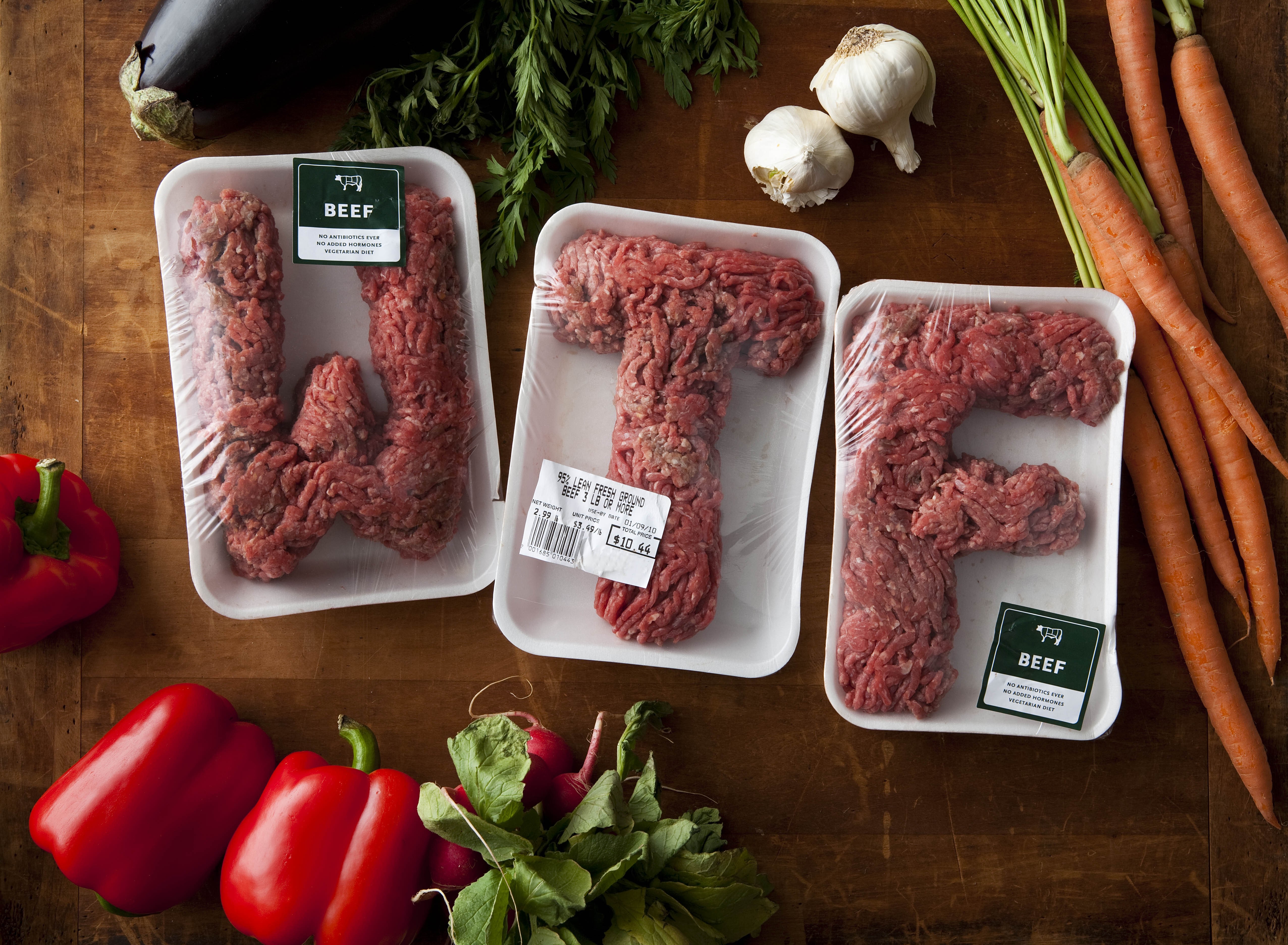 Ground beef arranged in letters on trays with produce HD Wallpaper