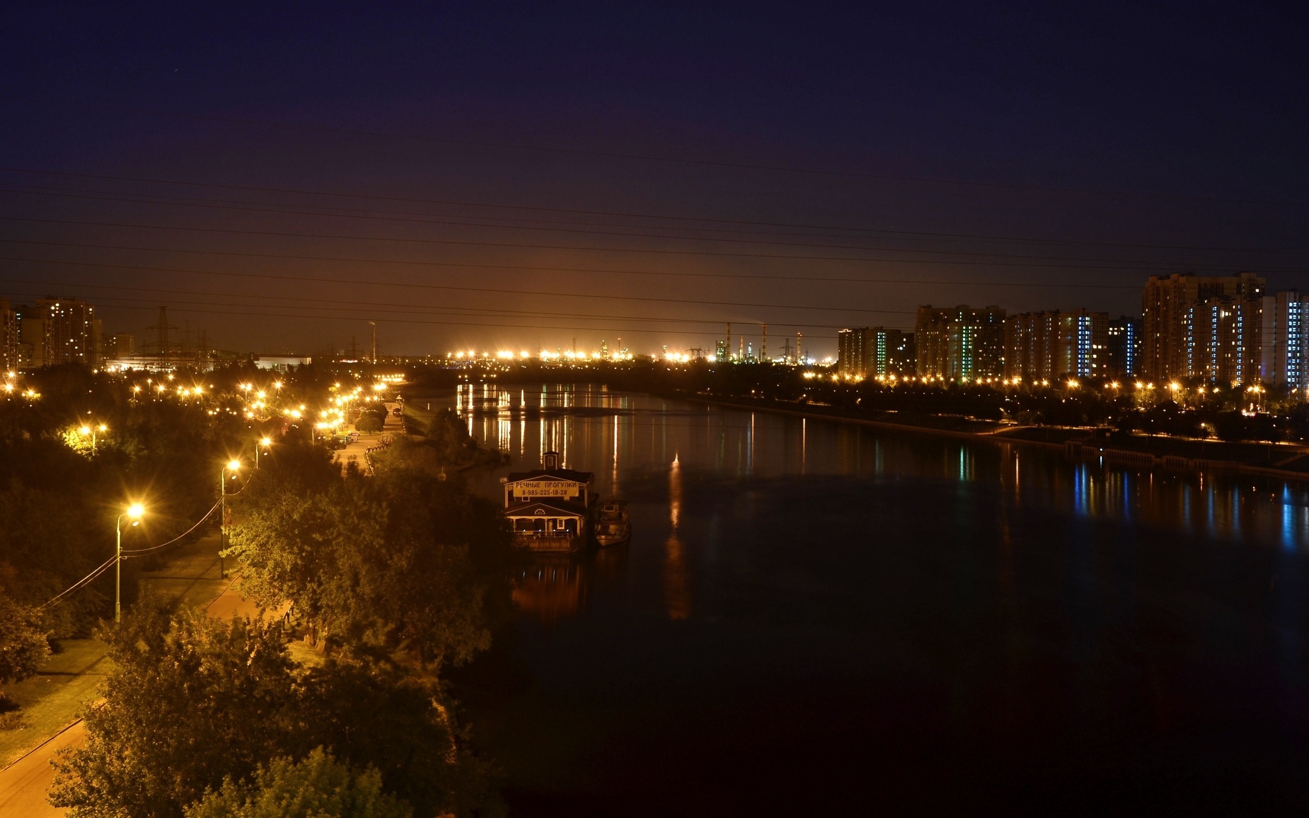 Cityscape at night with river and illuminated buildings HD Wallpaper