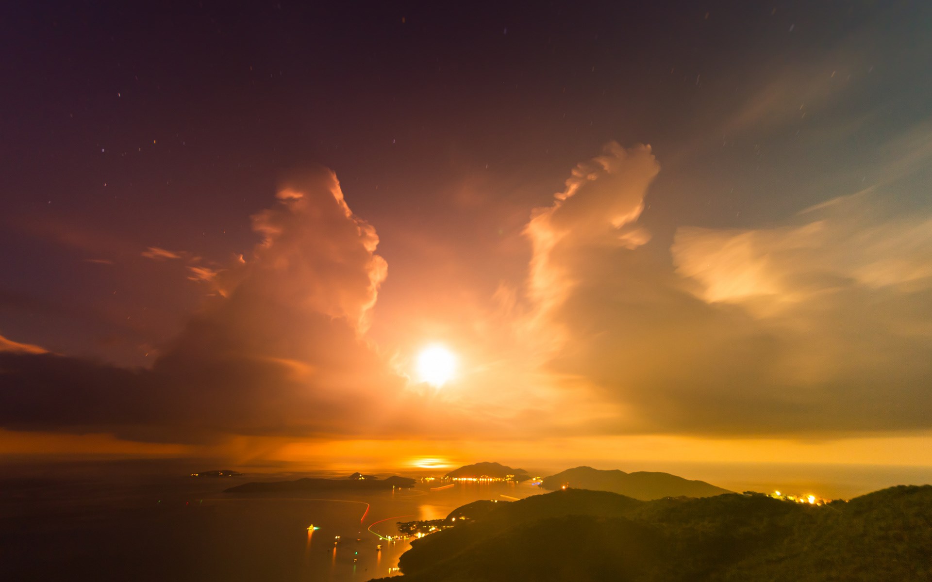 Night sky over a coastal town with mountains HD Wallpaper