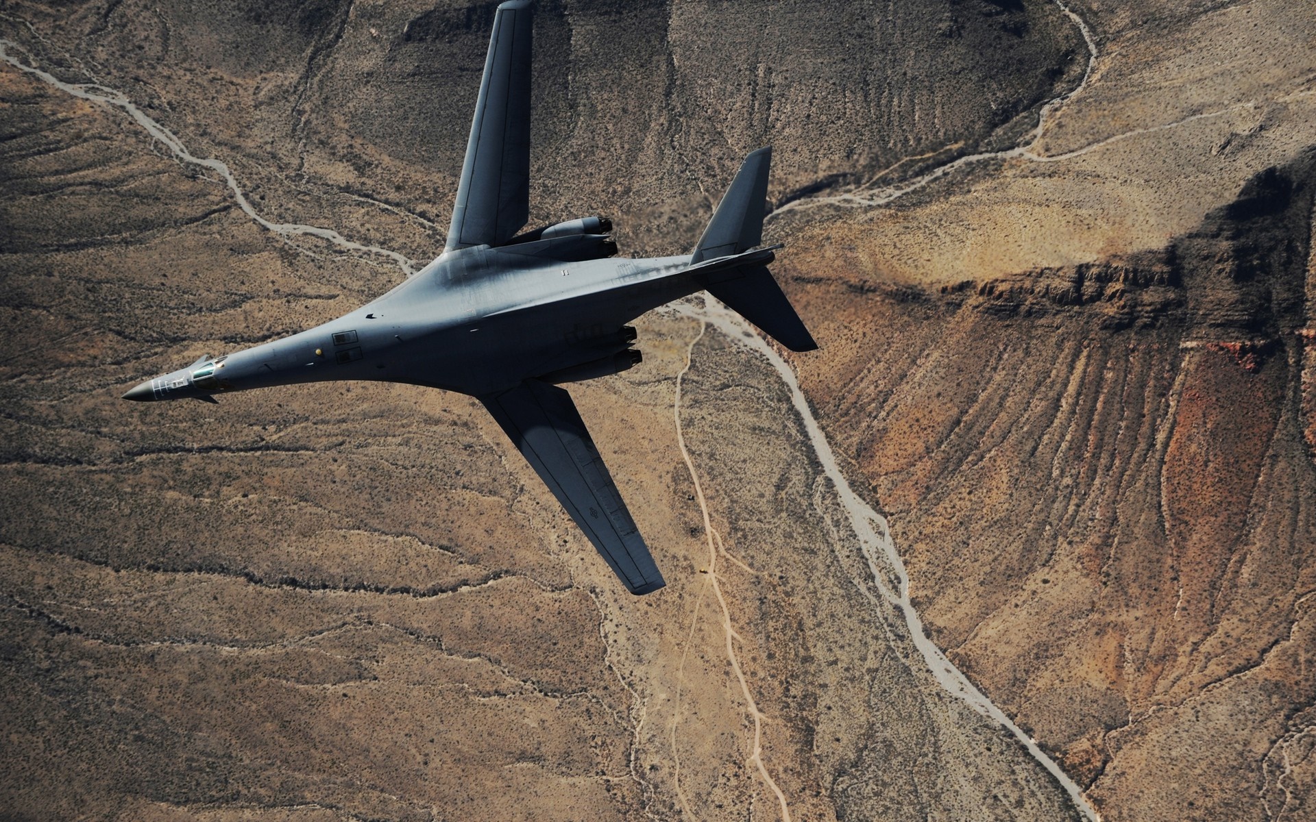 Rockwell B-1 Lancer bomber flying over desert canyon HD Wallpaper