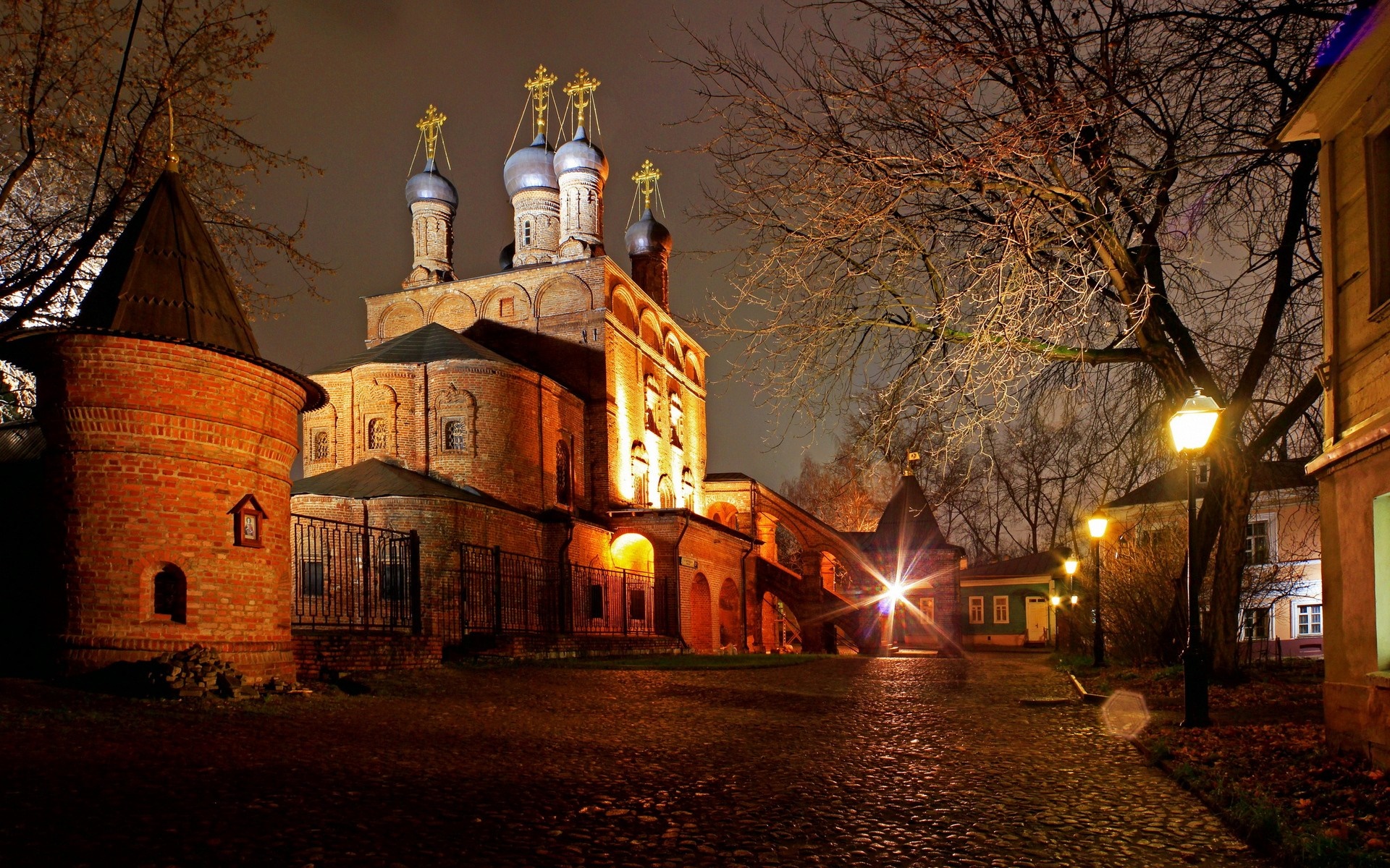 Night view of a historic brick church with onion domes and a cobblestone path. HD Wallpaper