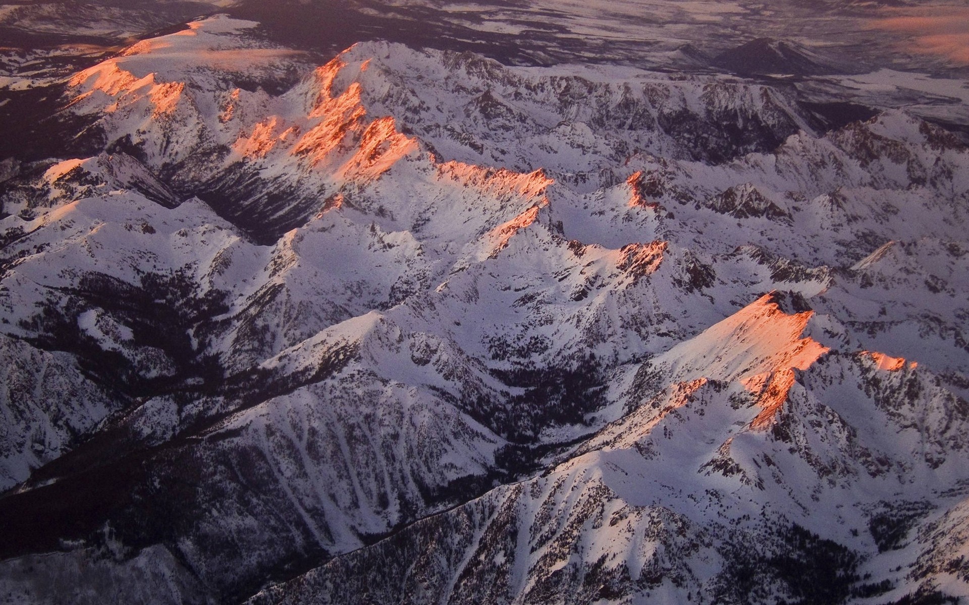 Snow-covered mountains illuminated by golden hour light HD Wallpaper