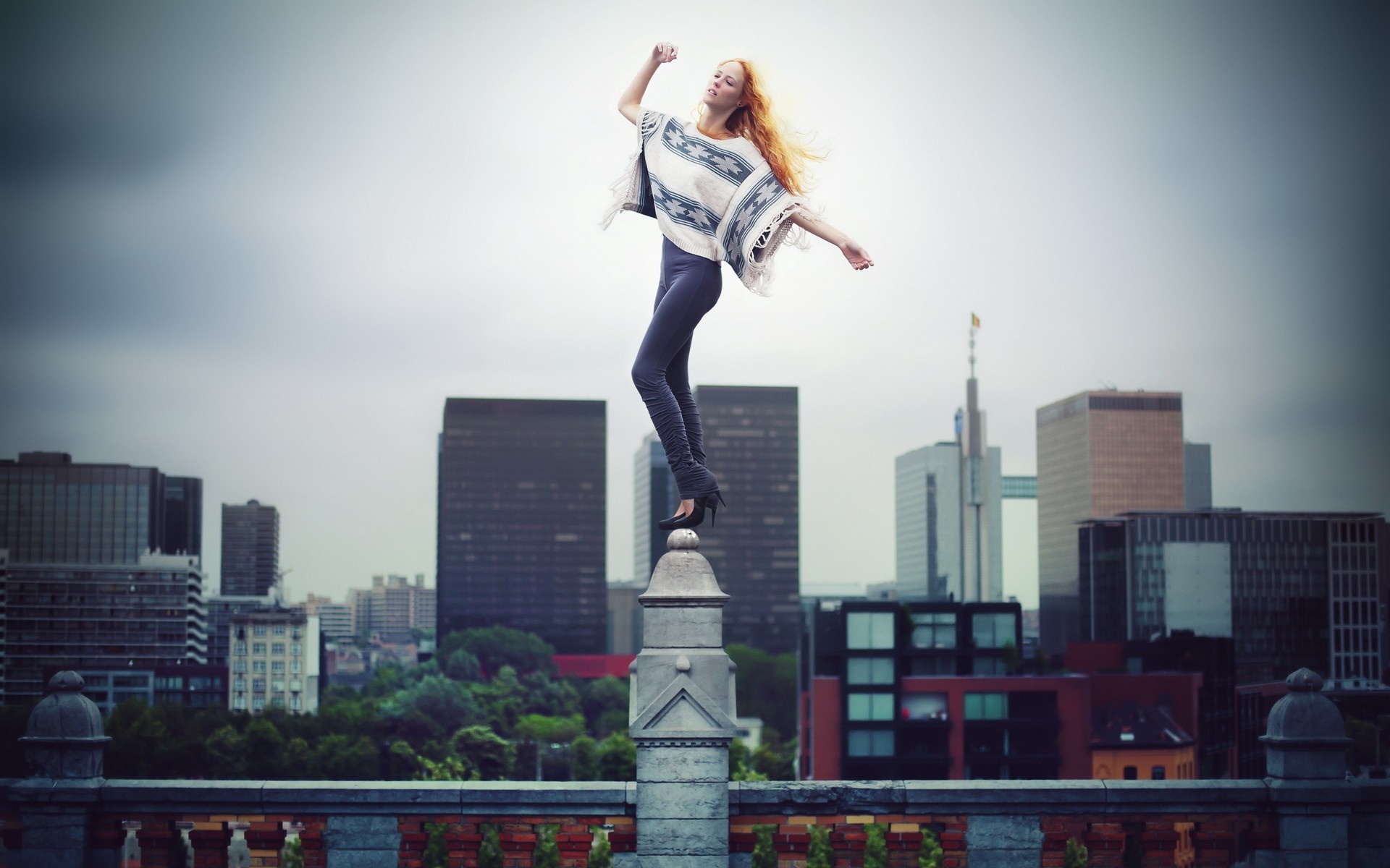 Woman posing on a pillar with a city skyline HD Wallpaper