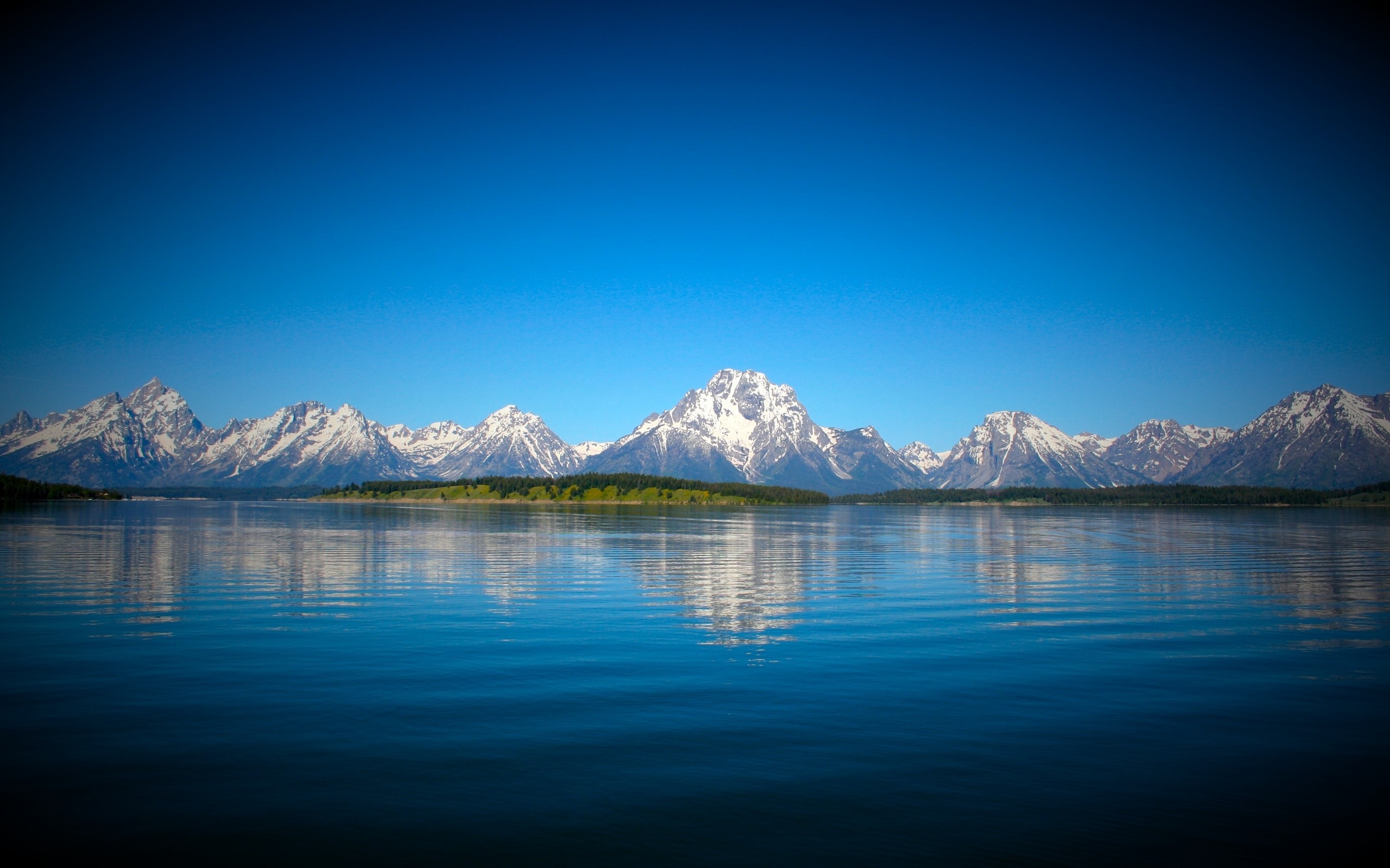 Snow-capped mountains reflected in a lake under a clear blue sky HD Wallpaper
