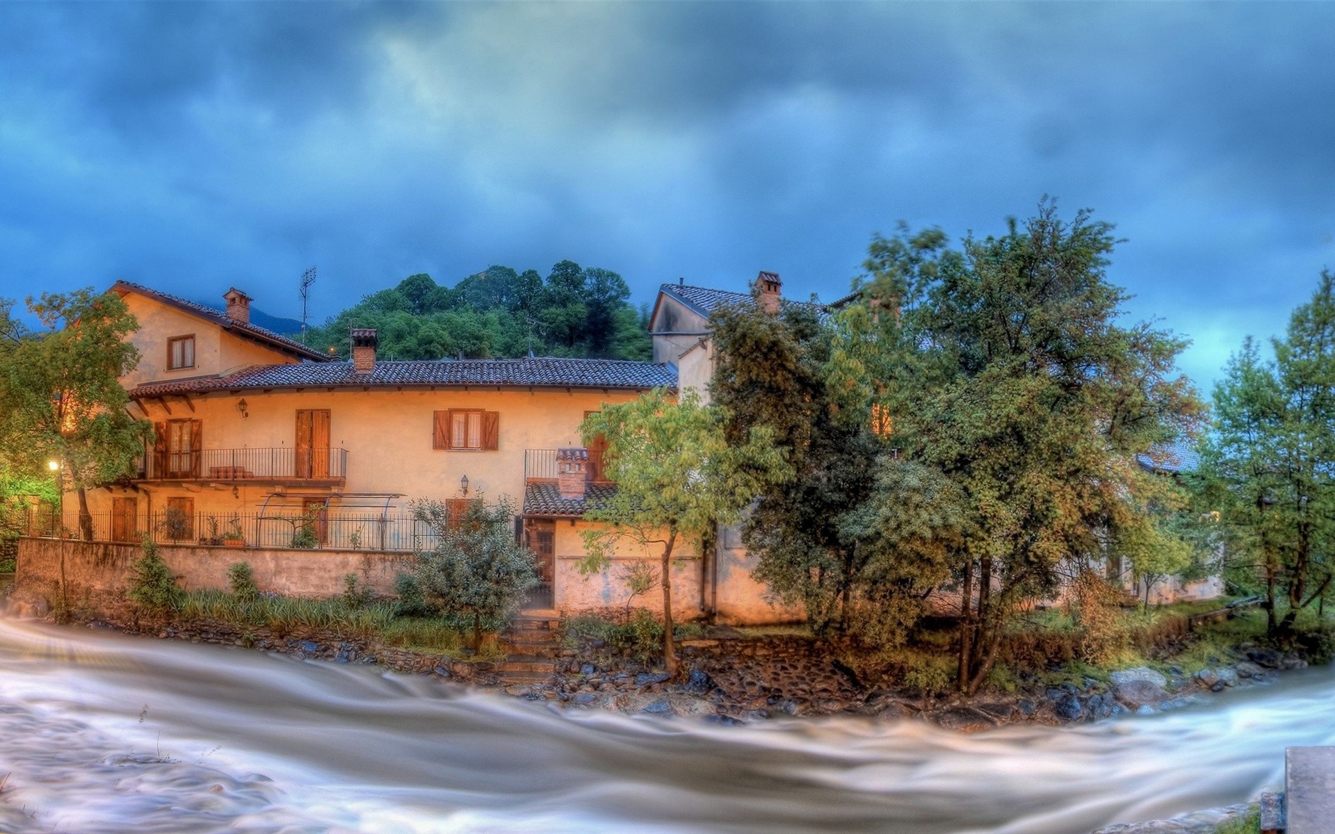 River flowing past houses in a rural village HD Wallpaper