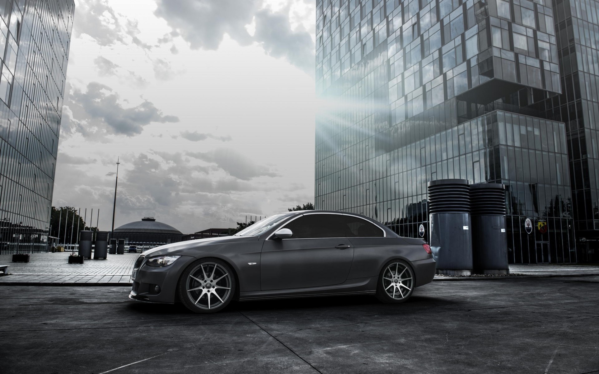 Gray BMW sports car parked in front of modern glass buildings HD Wallpaper