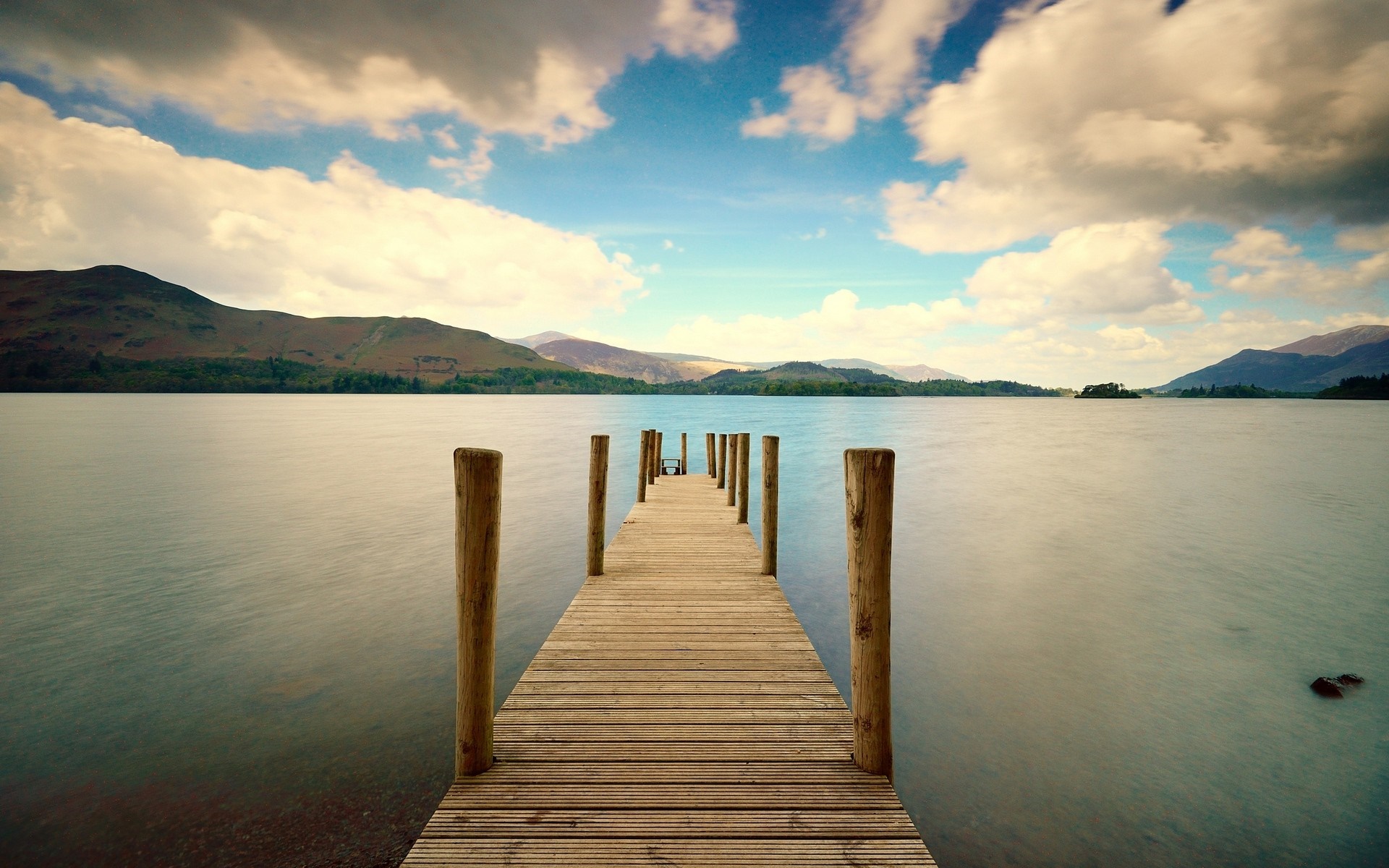 Wooden pier on a calm lake with mountains in the background HD Wallpaper