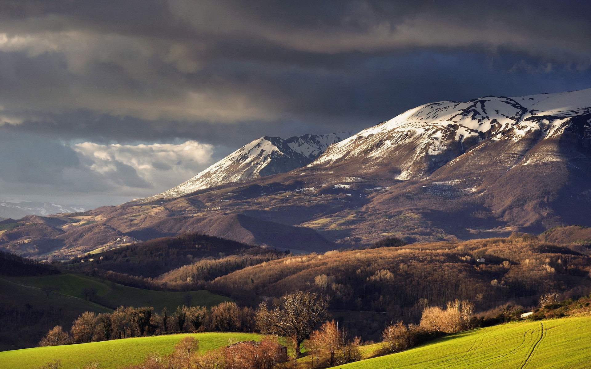 Sunlight on snow-capped mountains and rolling hills HD Wallpaper