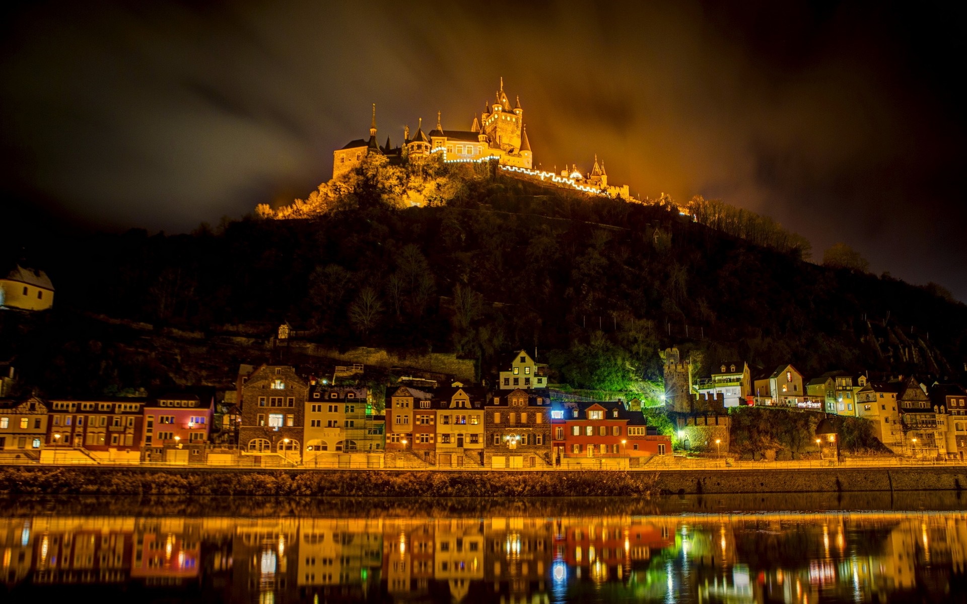 Castle on a hill overlooking a town at night HD Wallpaper