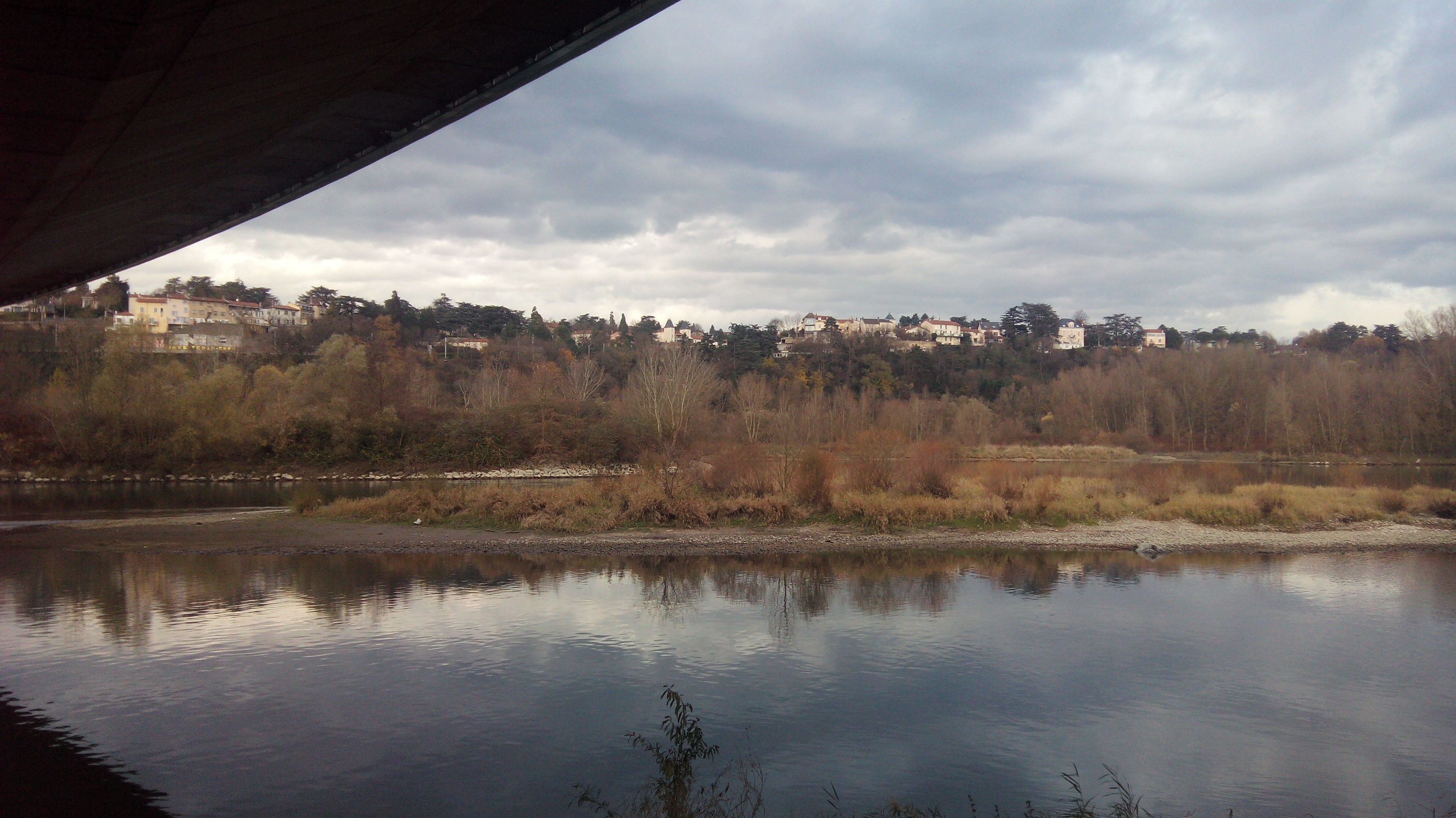 River landscape with town on hill under cloudy sky HD Wallpaper