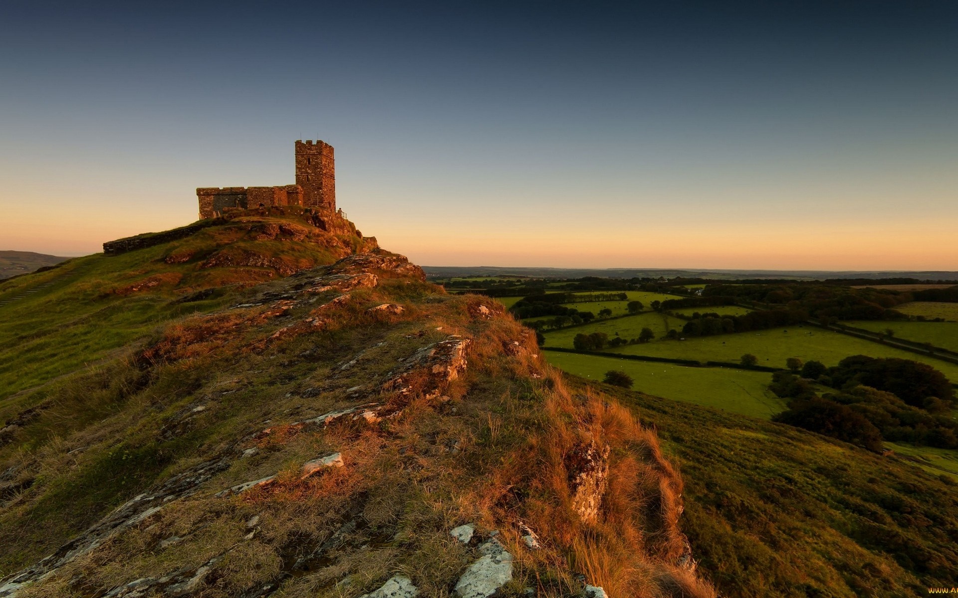 Castle on a hill at sunset overlooking fields HD Wallpaper