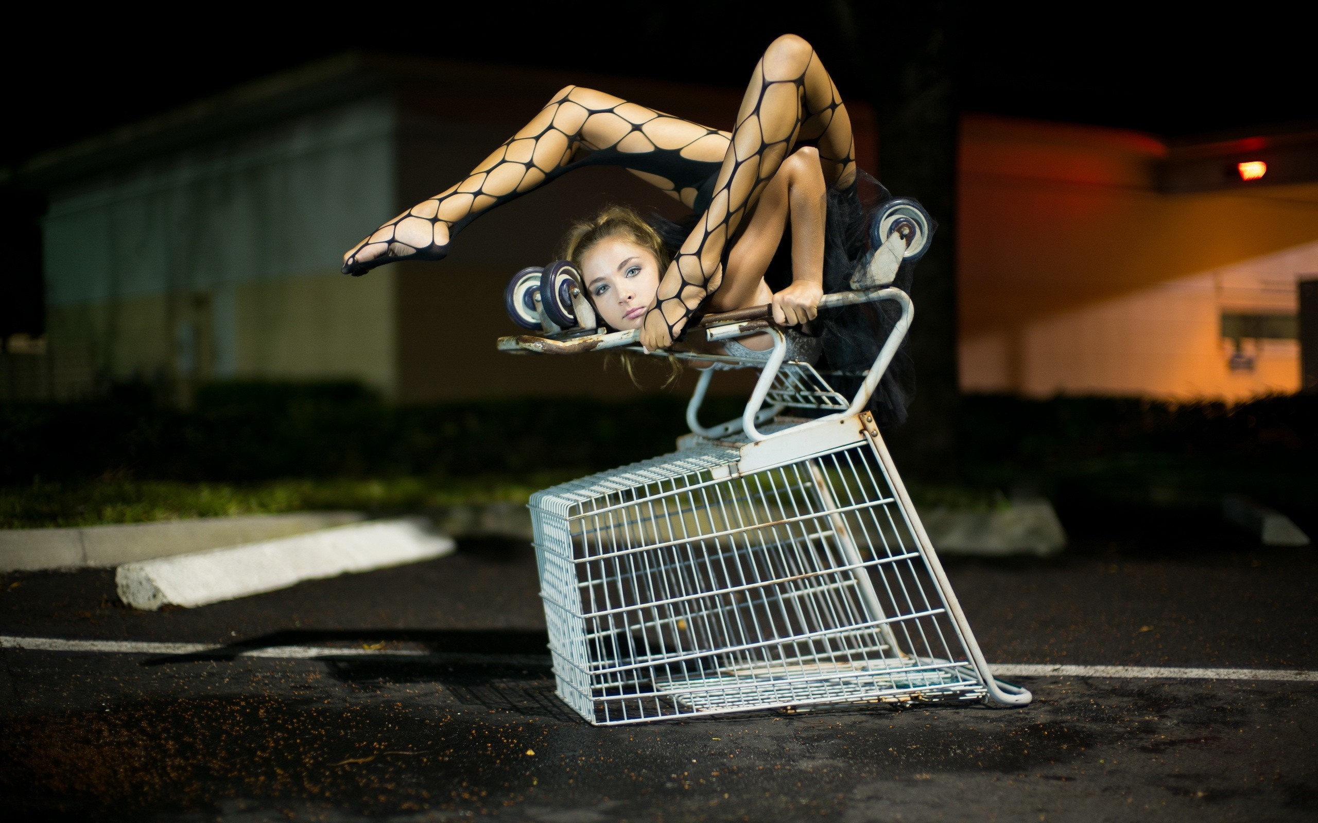 Woman contortionist in fishnet stockings in shopping cart HD Wallpaper