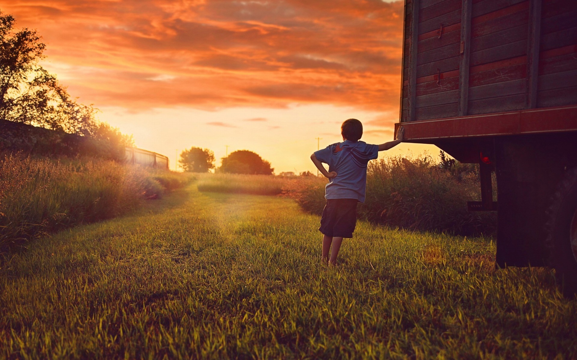 Boy leaning on truck at sunset in a field HD Wallpaper