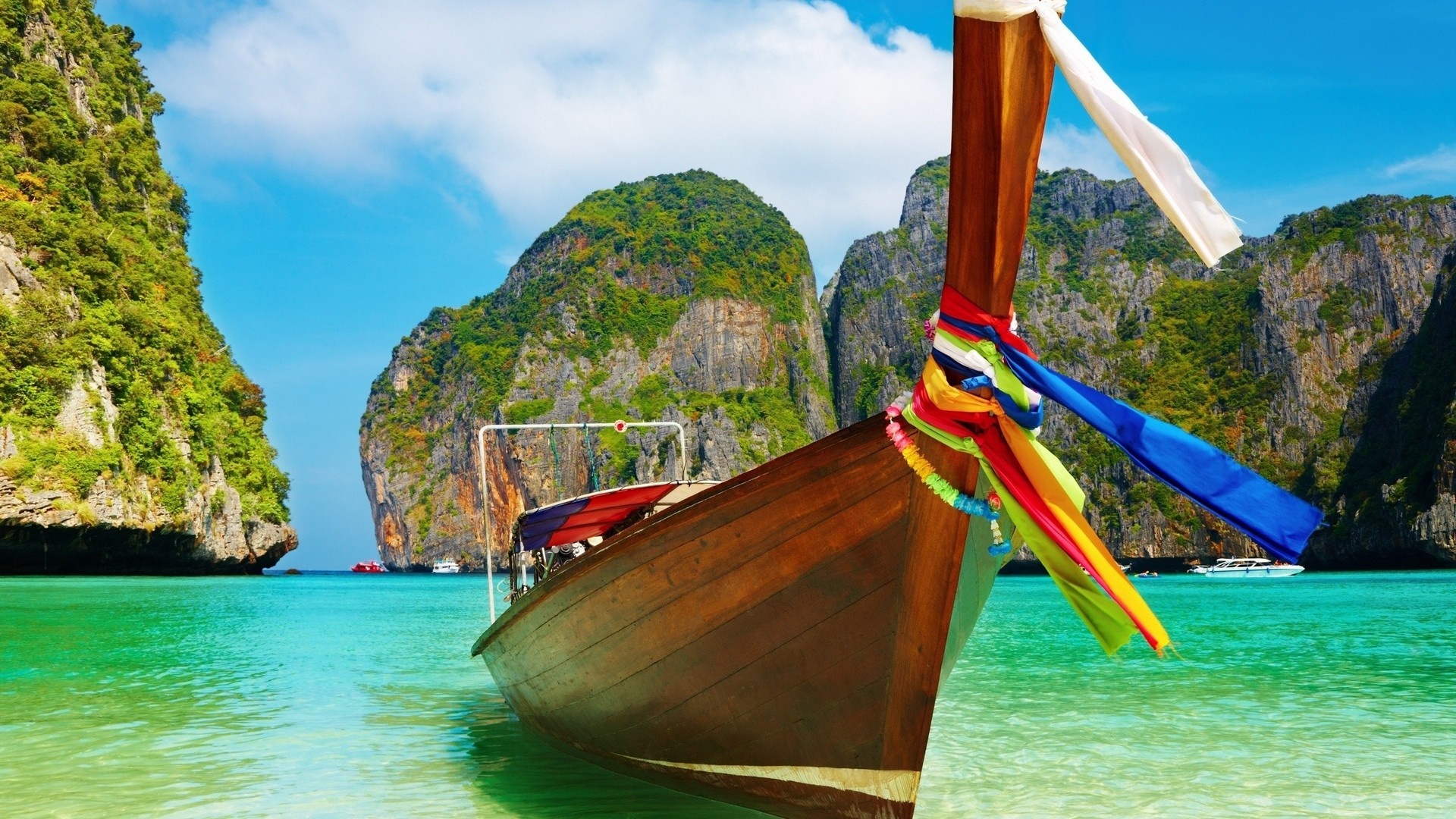 Long tail boat in a tropical bay with limestone cliffs HD Wallpaper