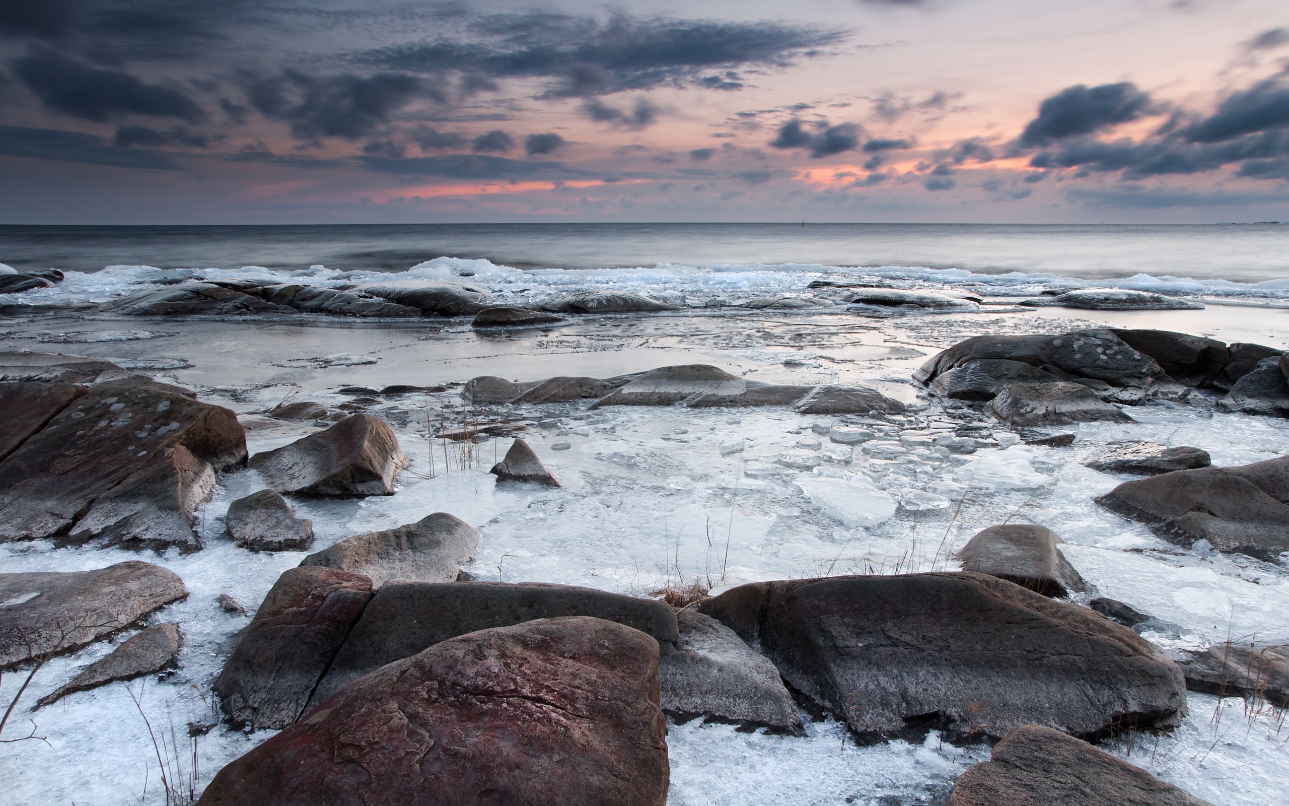 Rocky shore with ice and ocean at sunset HD Wallpaper
