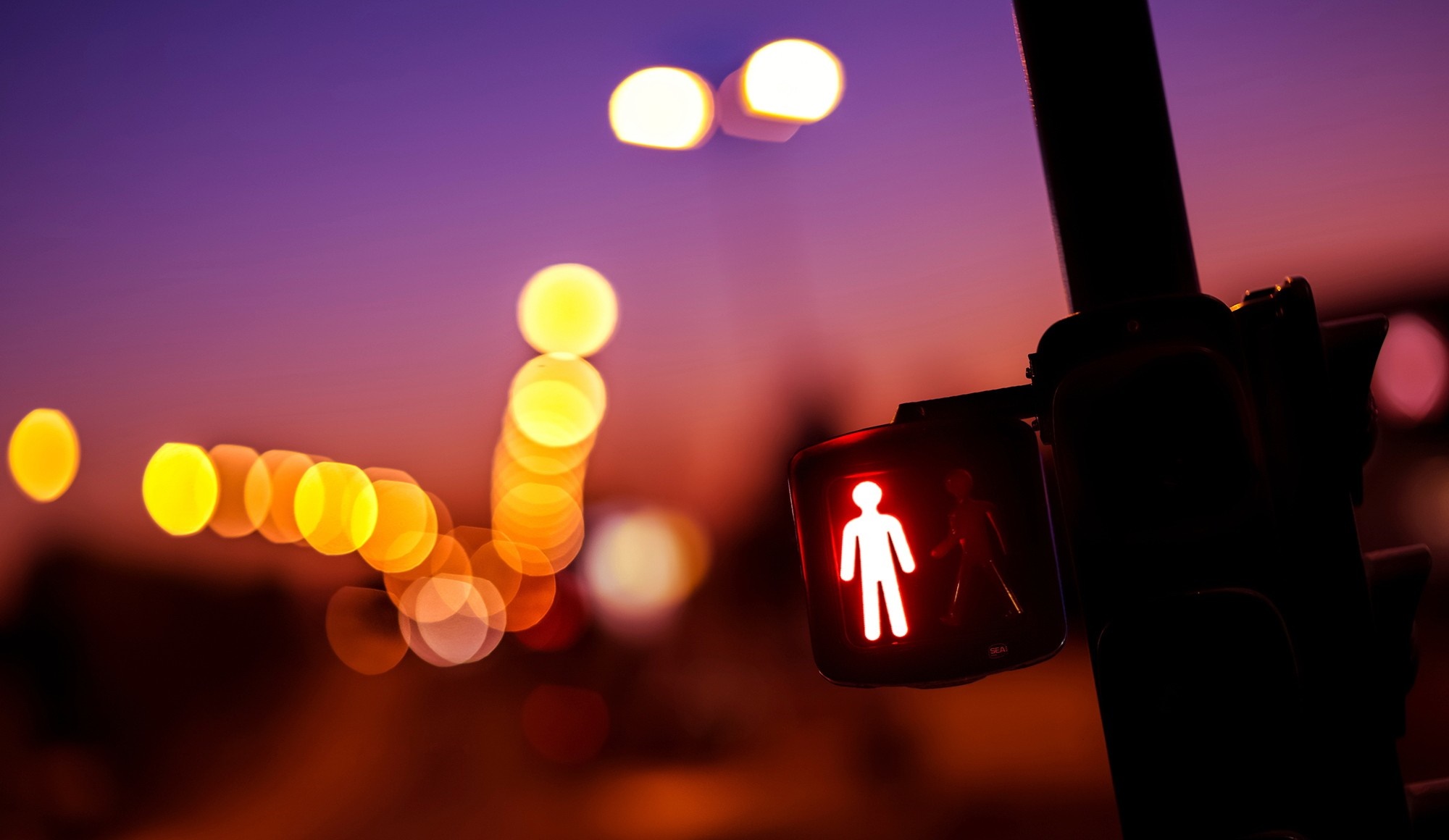Red pedestrian crossing light at dusk with bokeh lights HD Wallpaper