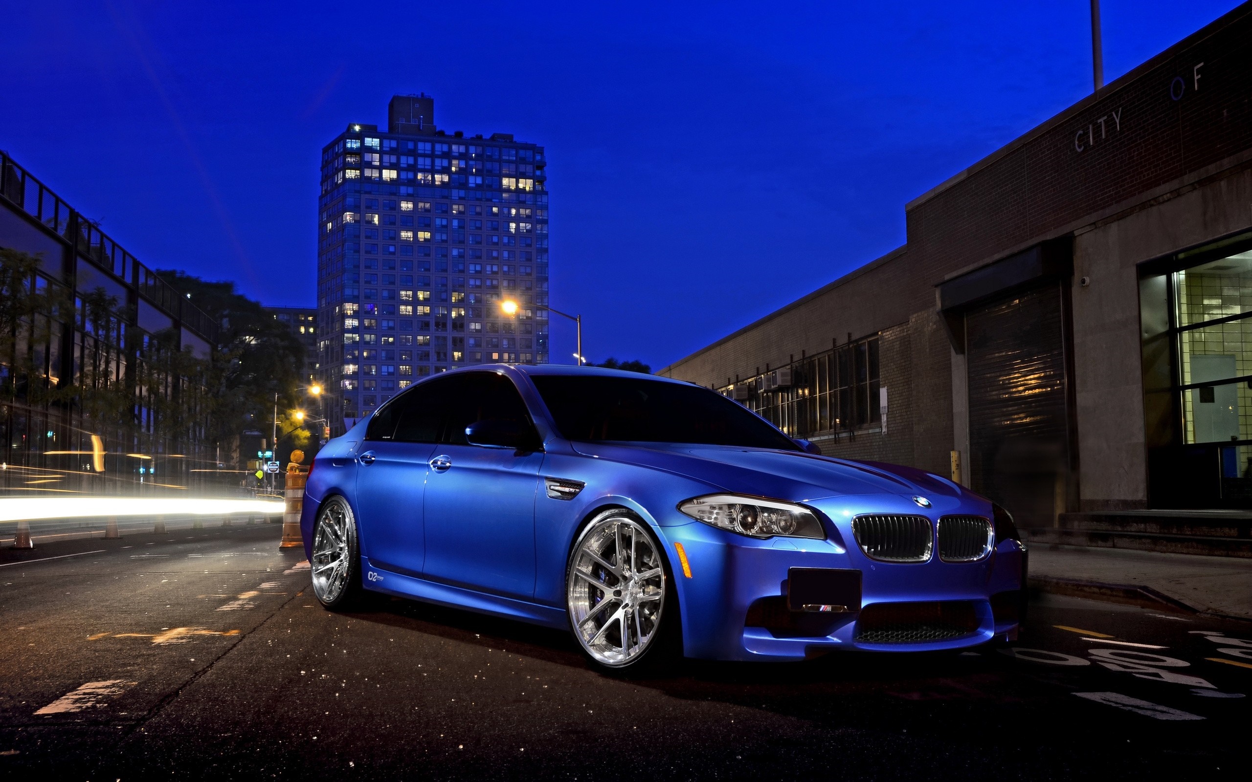Blue BMW M5 parked on city street at night HD Wallpaper