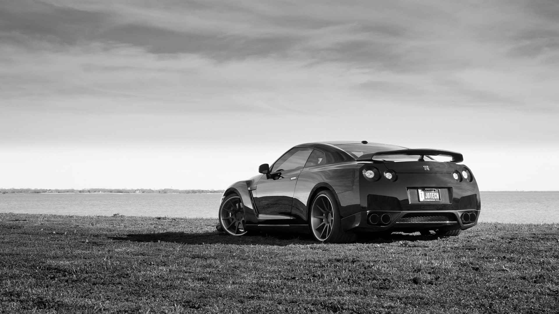 Nissan GT-R parked on grass by the water HD Wallpaper